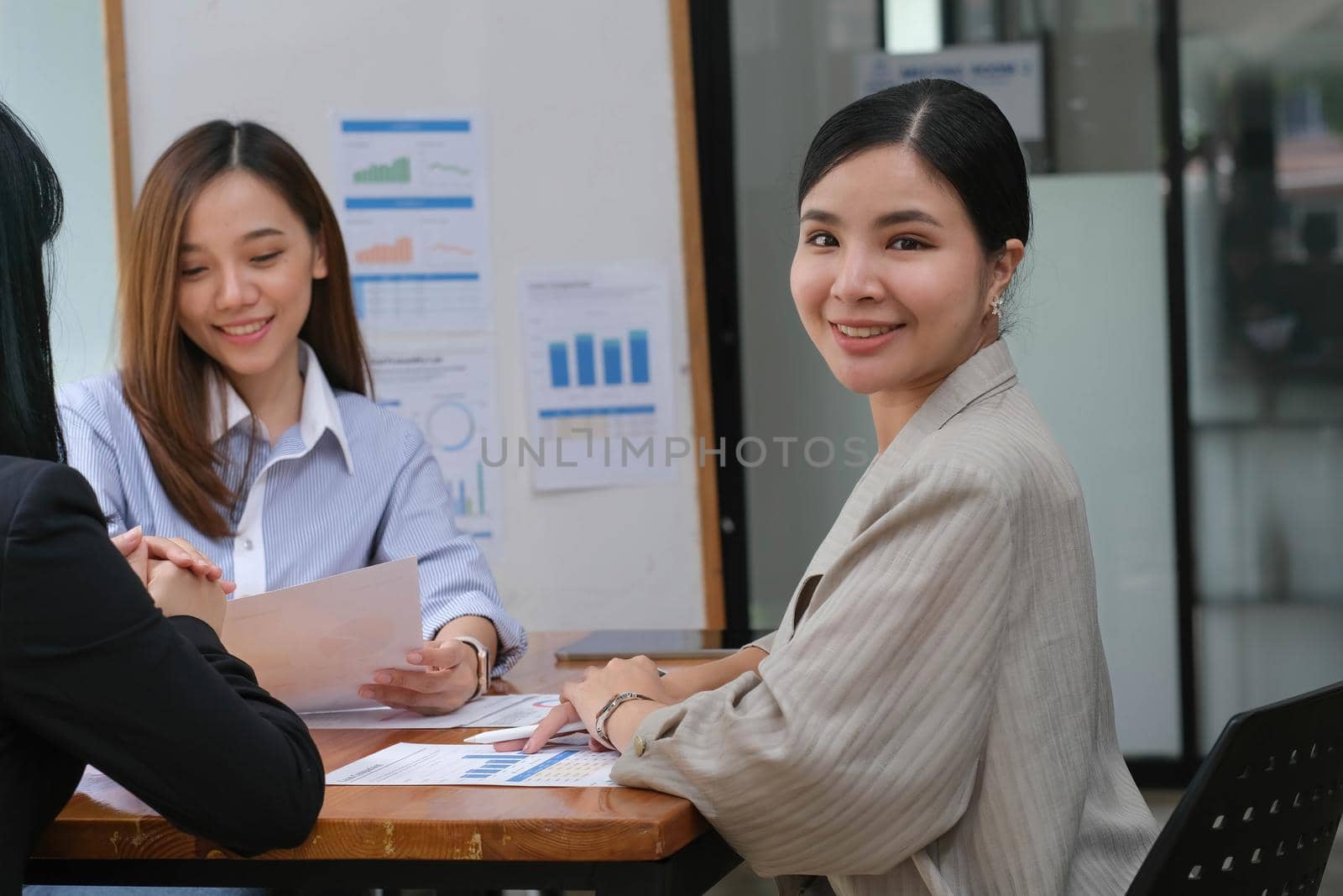 A young asian woman is having a business meeting with her team colleagues in a conference room..