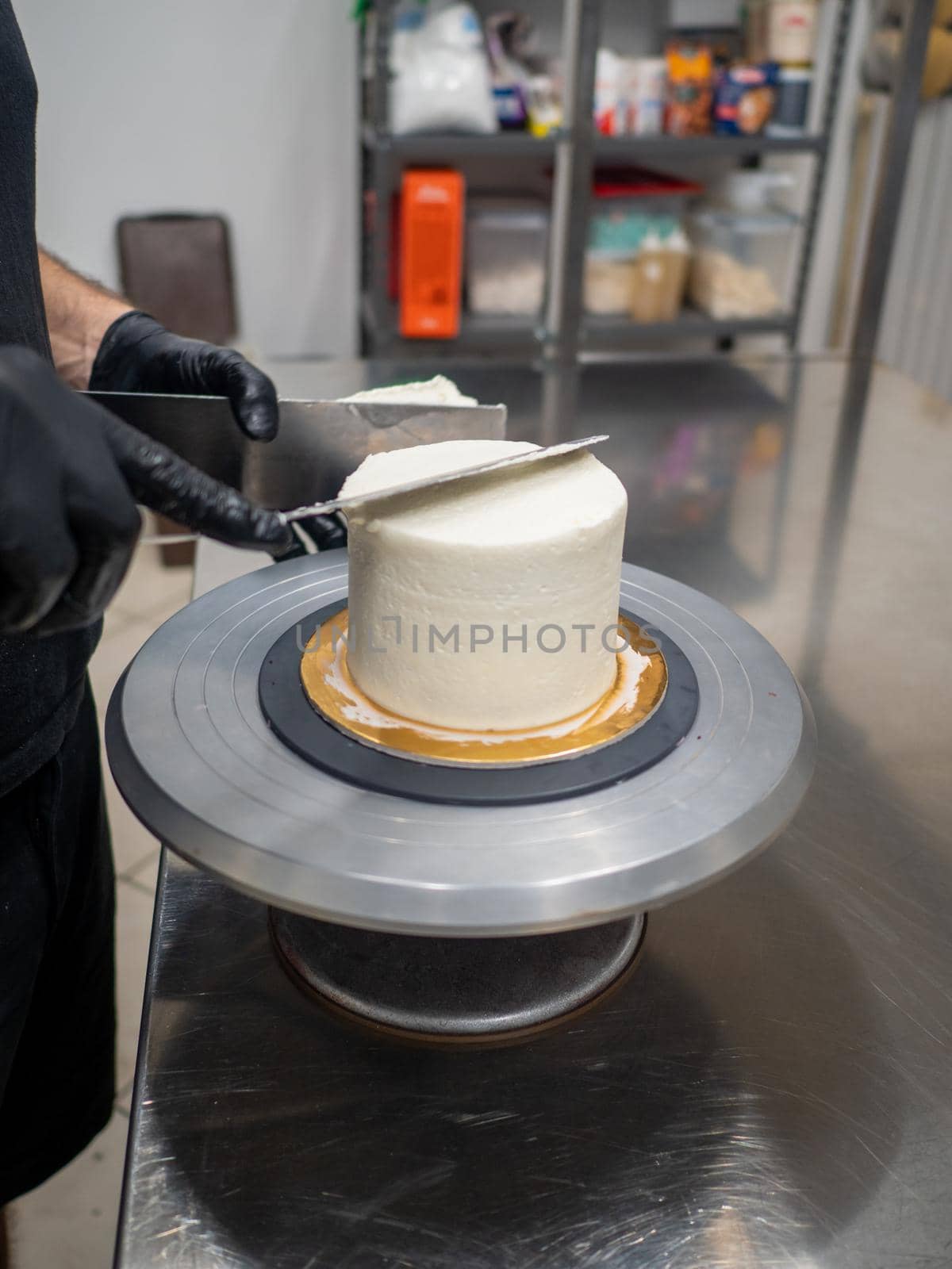 Decorator using spatula and scraper to smooth buttercream on a frosted cake