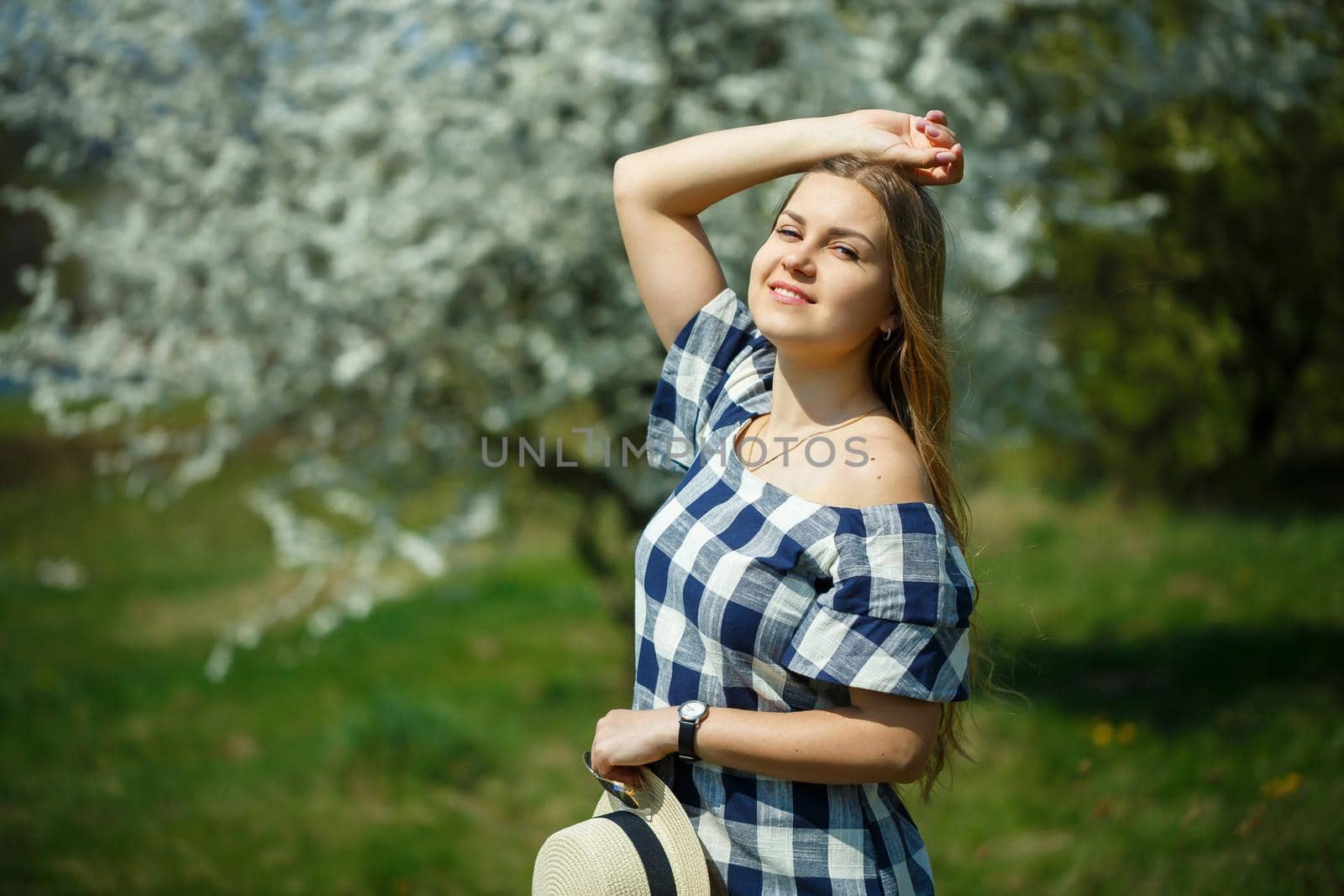 A girl with a beautiful spring smile against a flowering tree