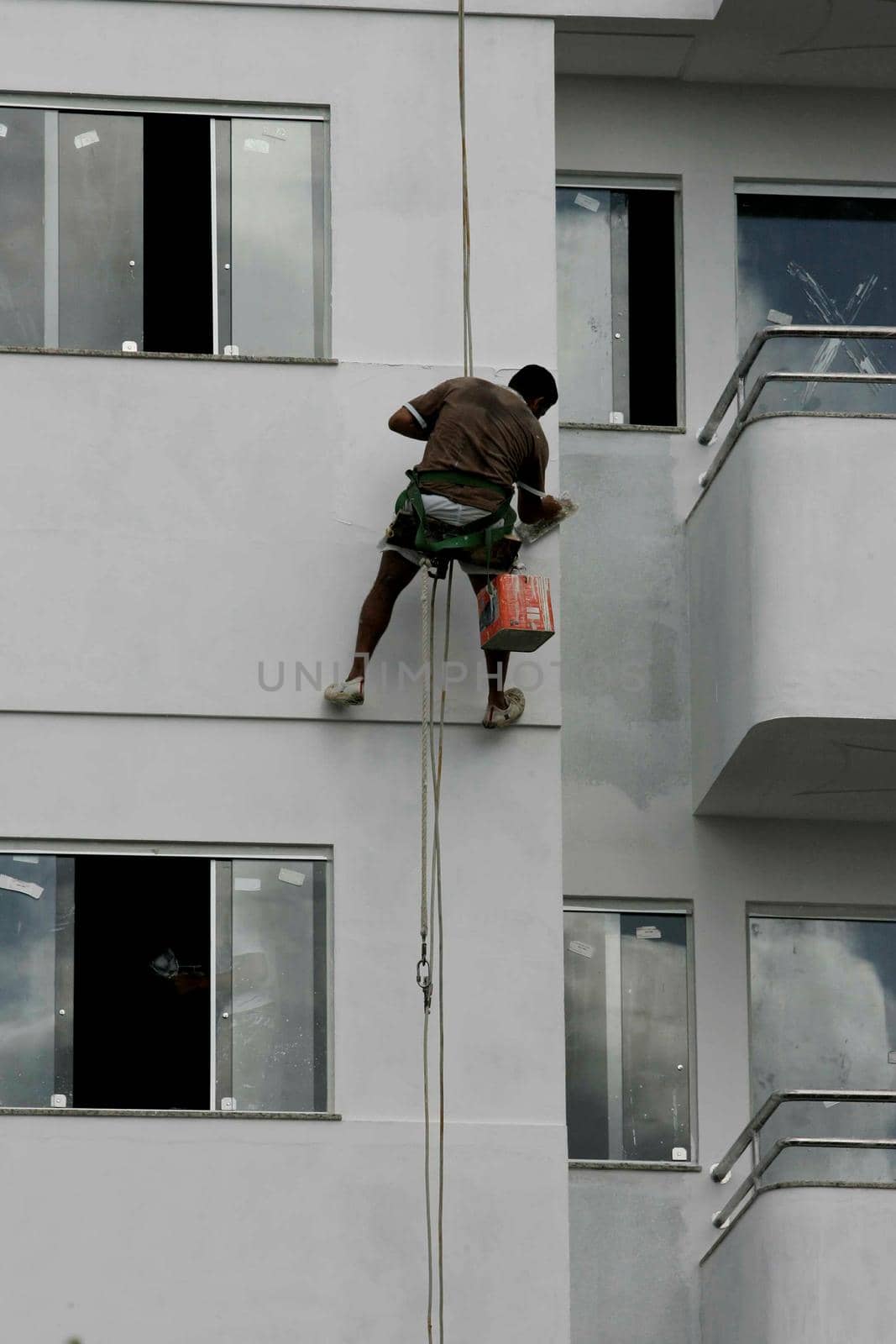 eunapolis, bahia / brazil - august 25, 2009: Wall painter is seen hanging during painting of a building in the city of Eunapolis.