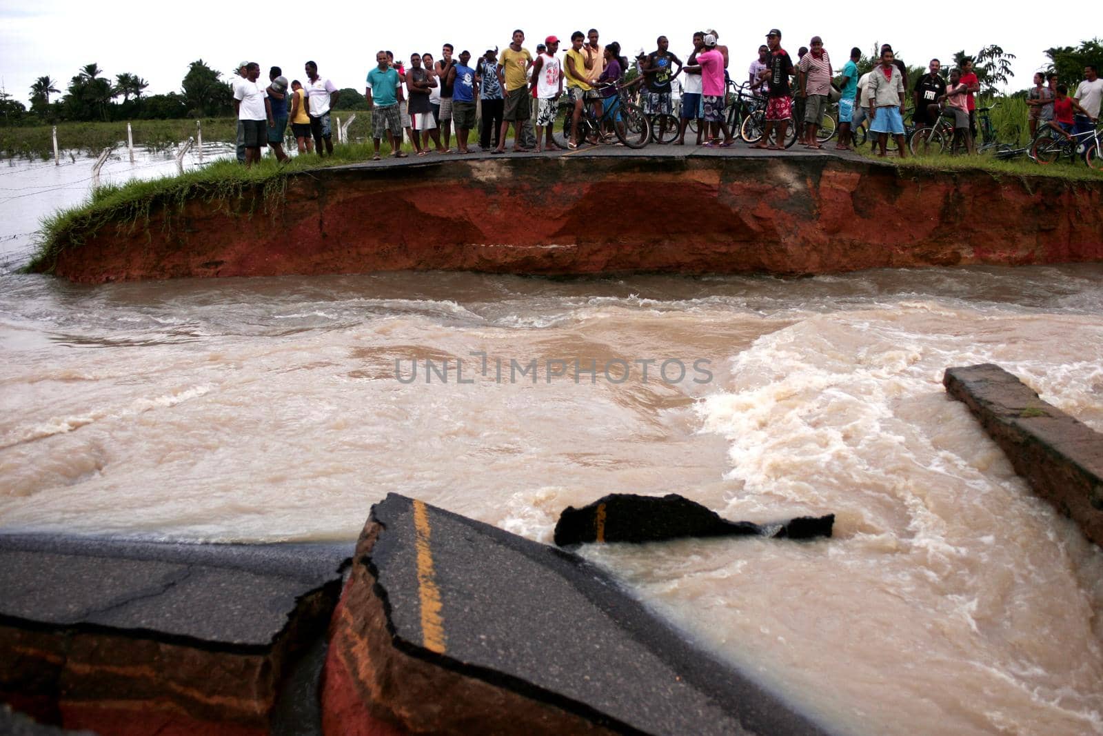 prado, bahia, brazil - april 7, 2010: people trying to cross a road destroyed due to flooding of a river in the city of Prado