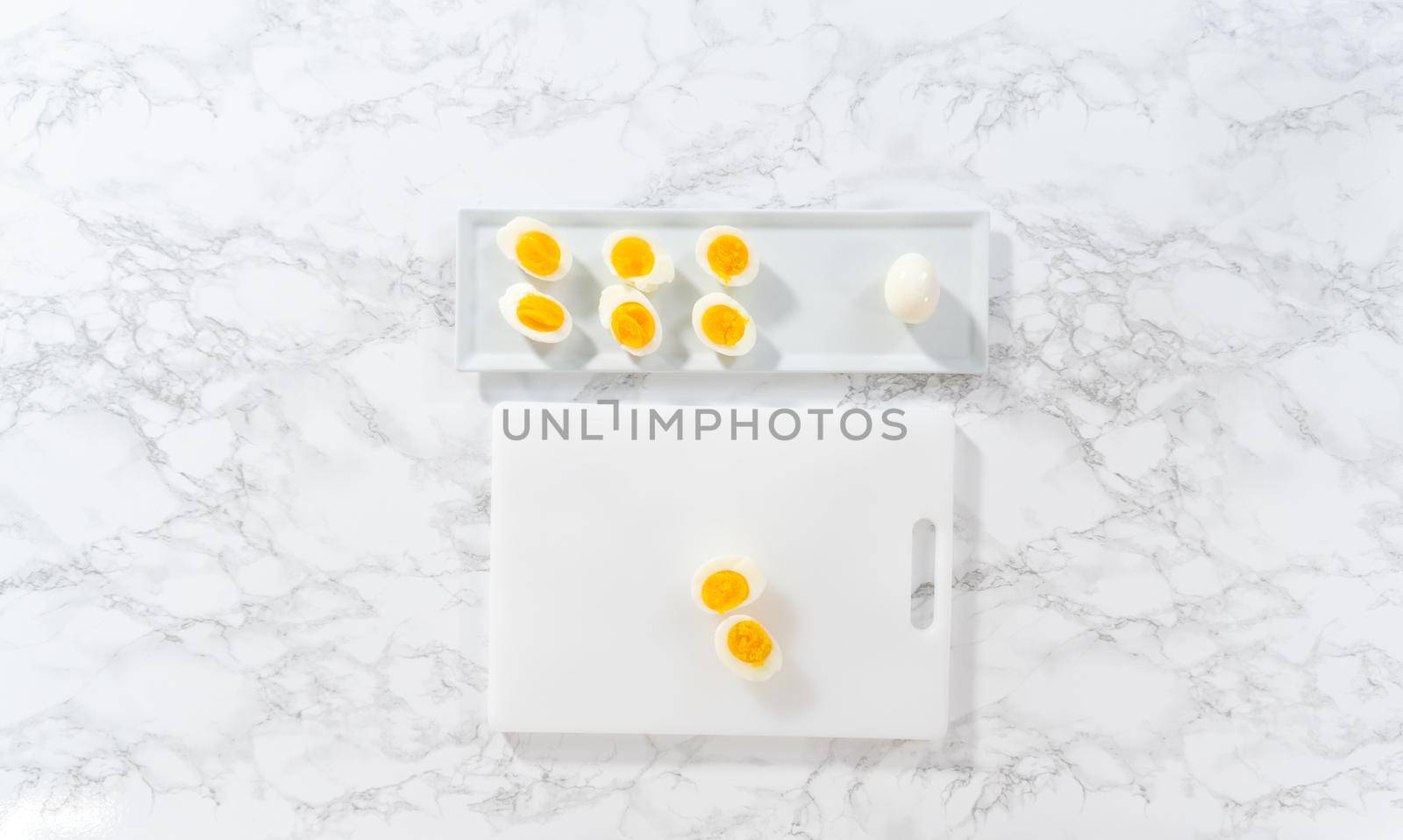 Slicing hard-boiled eggs on a white cutting board.