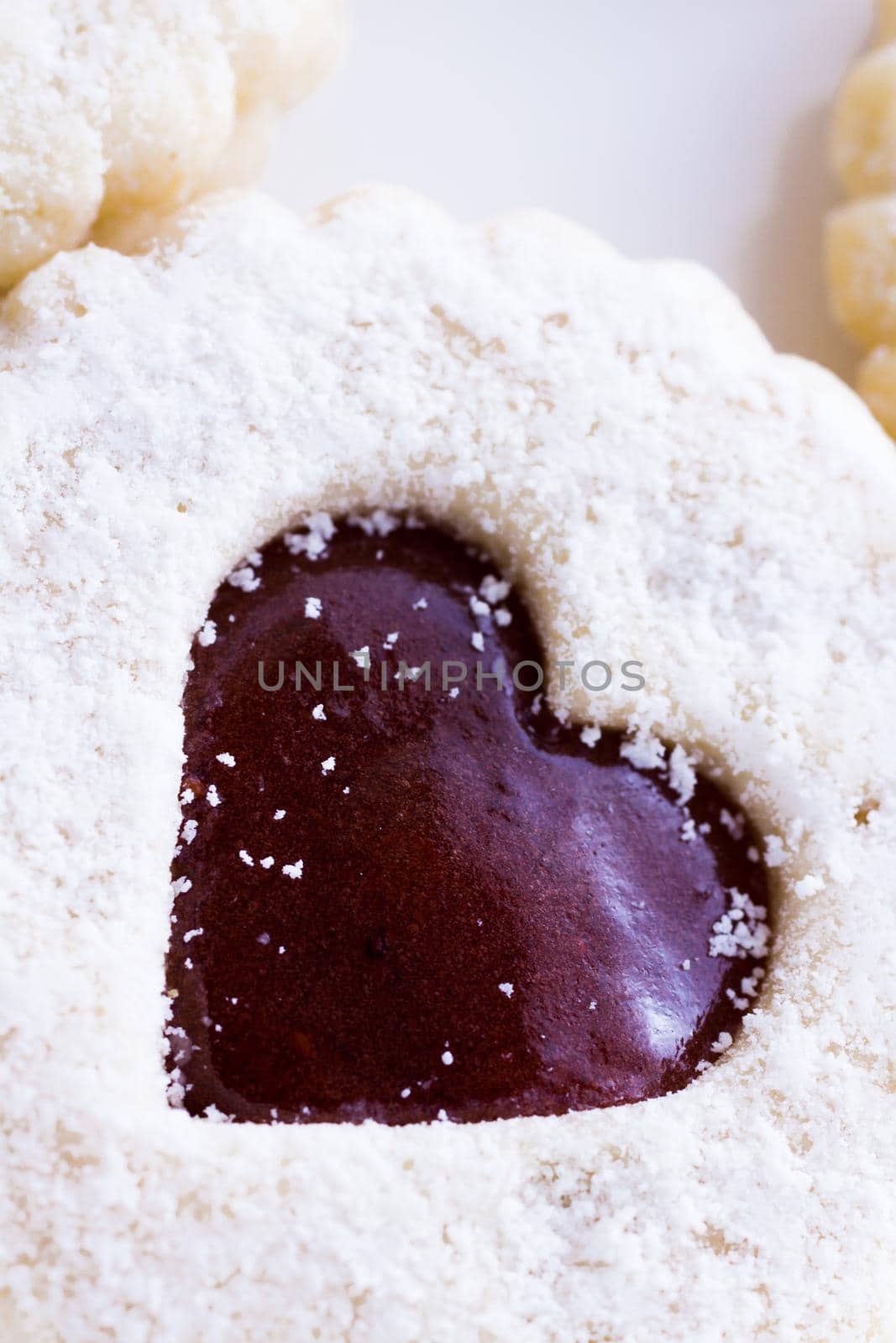 Linzer Torte cookies on white background with powdered sugar sprinkled on top.