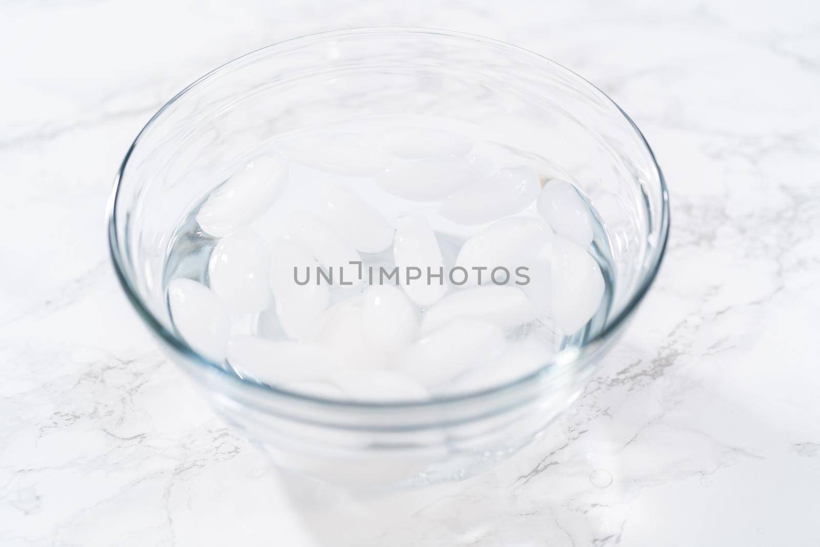 Cooling hard-boiled eggs in a glass bowl with cold water and ice cubes.