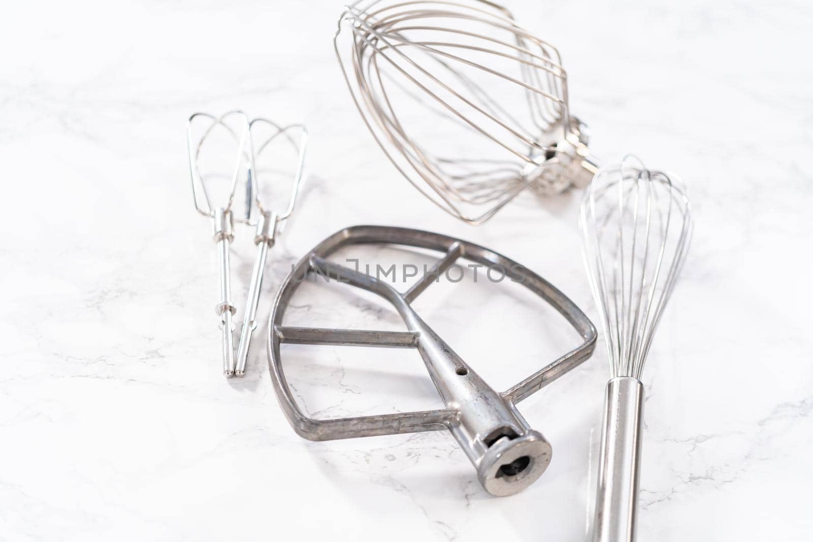 Close-up view. Variety of blending whisks on a marble countertop.