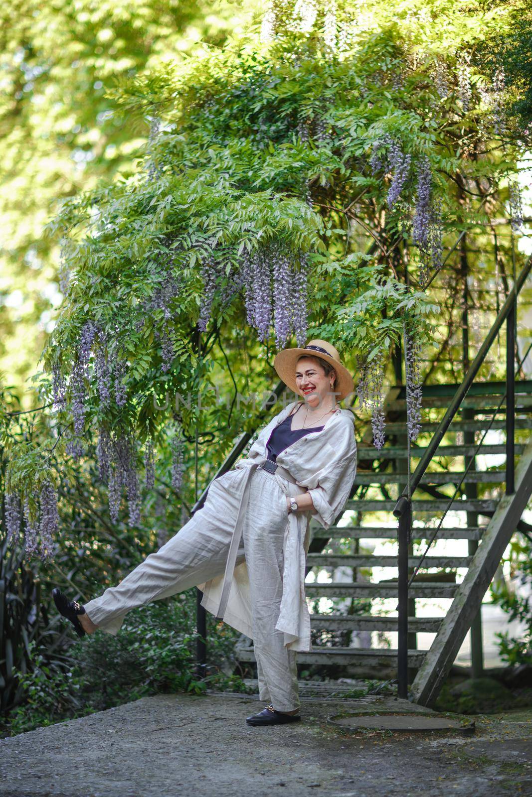 Thoughtful happy mature woman surrounded by chinese wisteria.