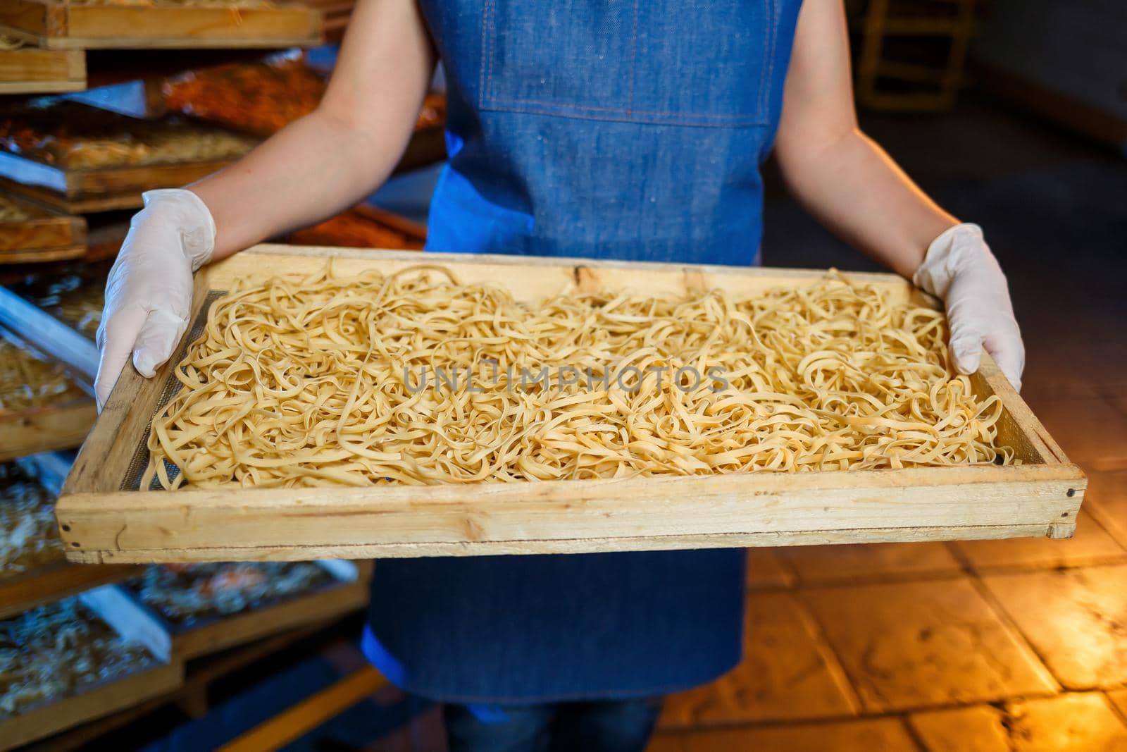 Worker with a box of pasta. The girl works on the production of spaghetti. Making noodles. Pasta factory.
