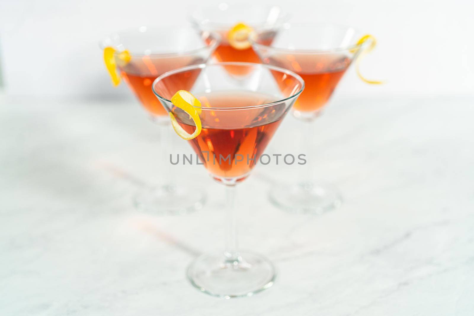 Cosmopolitan cocktail in a martini glass and decorated with a lemon swirl.