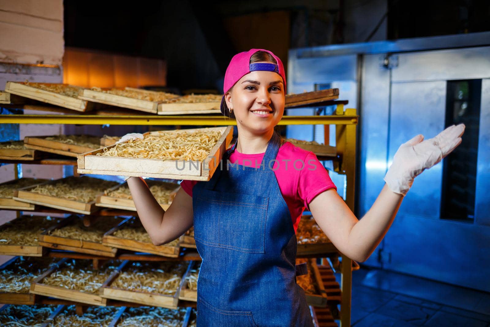 The girl works on the production of spaghetti. Making noodles. Pasta factory. Stage production of pasta. Raw noodles. Worker with a box of pasta.