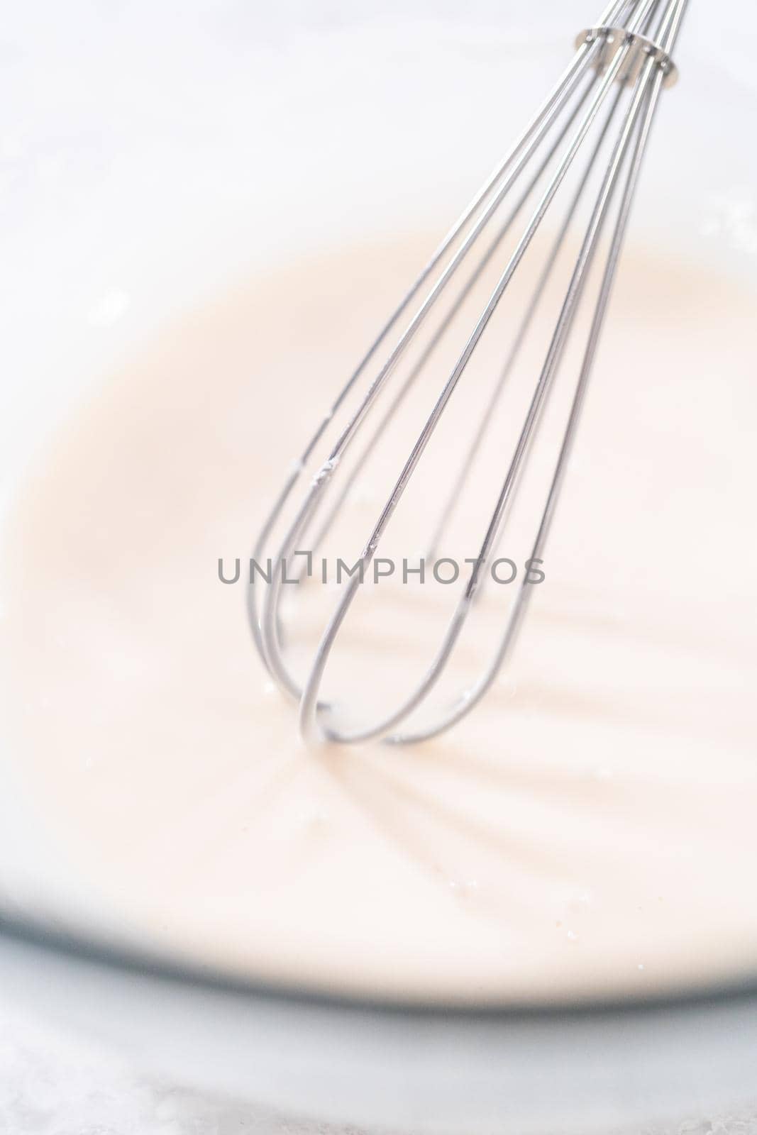 Mixing ingredients in a glass mixing bowl to prepare the white glaze.