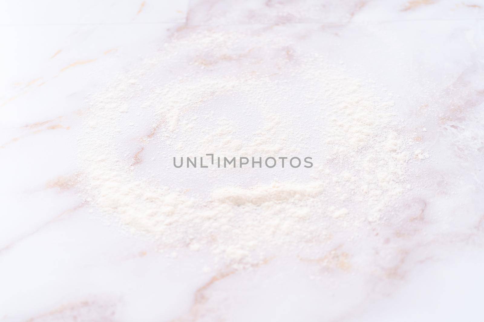 White flour sprinkled over the pink marble surface during the baking.