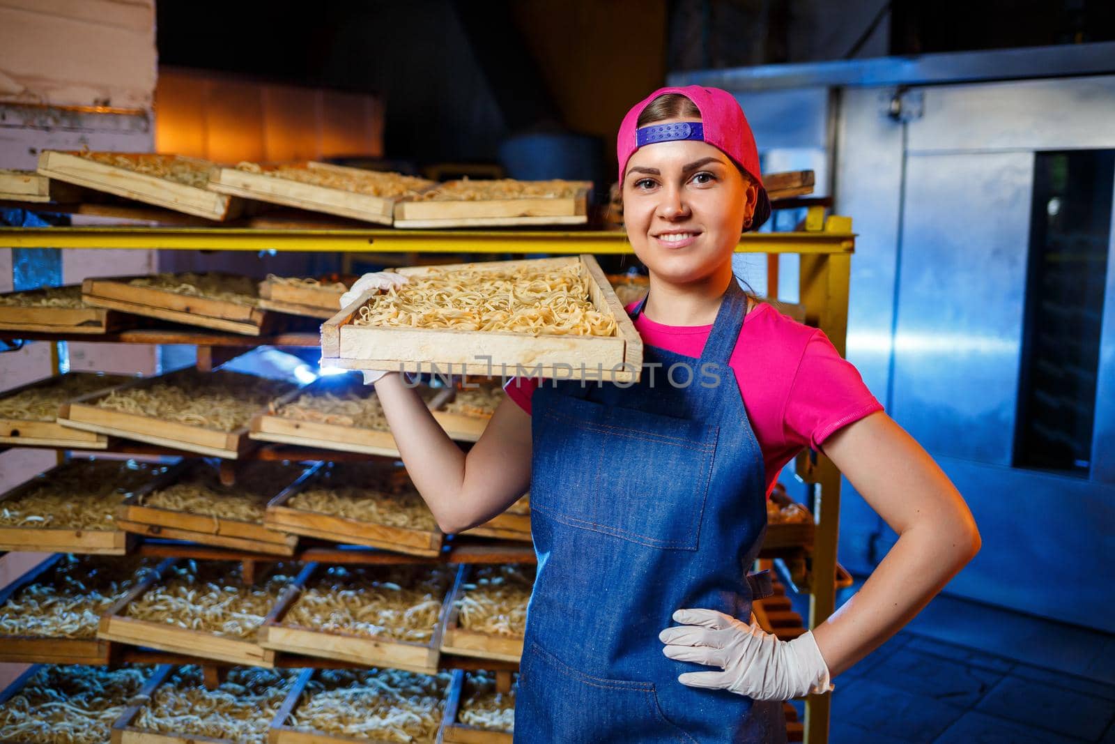 The girl works on the production of spaghetti. Making noodles. Pasta factory. Stage production of pasta. Raw noodles. Worker with a box of pasta.