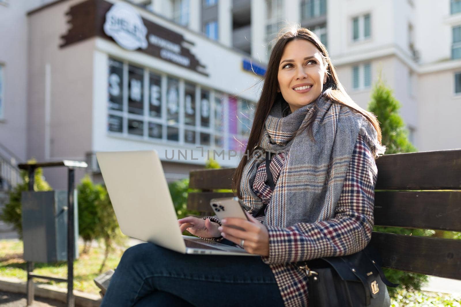 portrait of a successful young business woman working online on a laptop with a cup of coffee and looking into the distance with a smile.