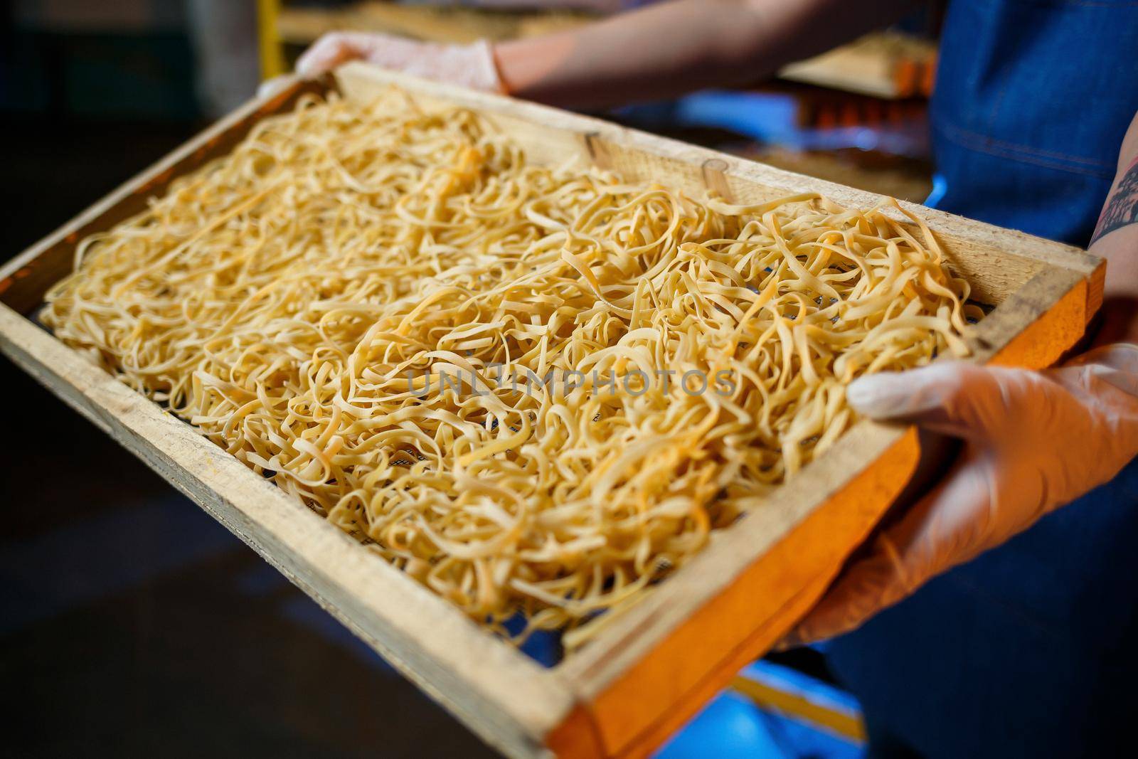 Worker with a box of pasta. The girl works on the production of spaghetti. Making noodles. Pasta factory.