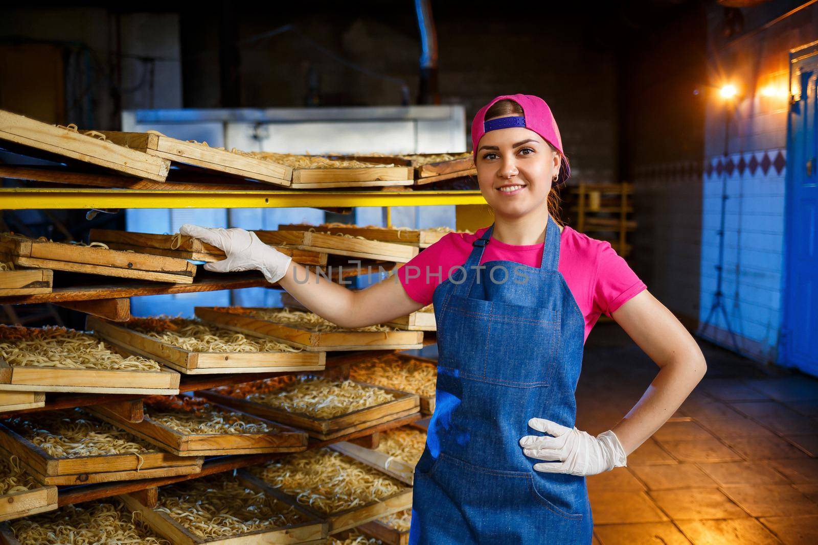 Worker with a box of pasta. The girl works on the production of spaghetti. Making noodles. Pasta factory.
