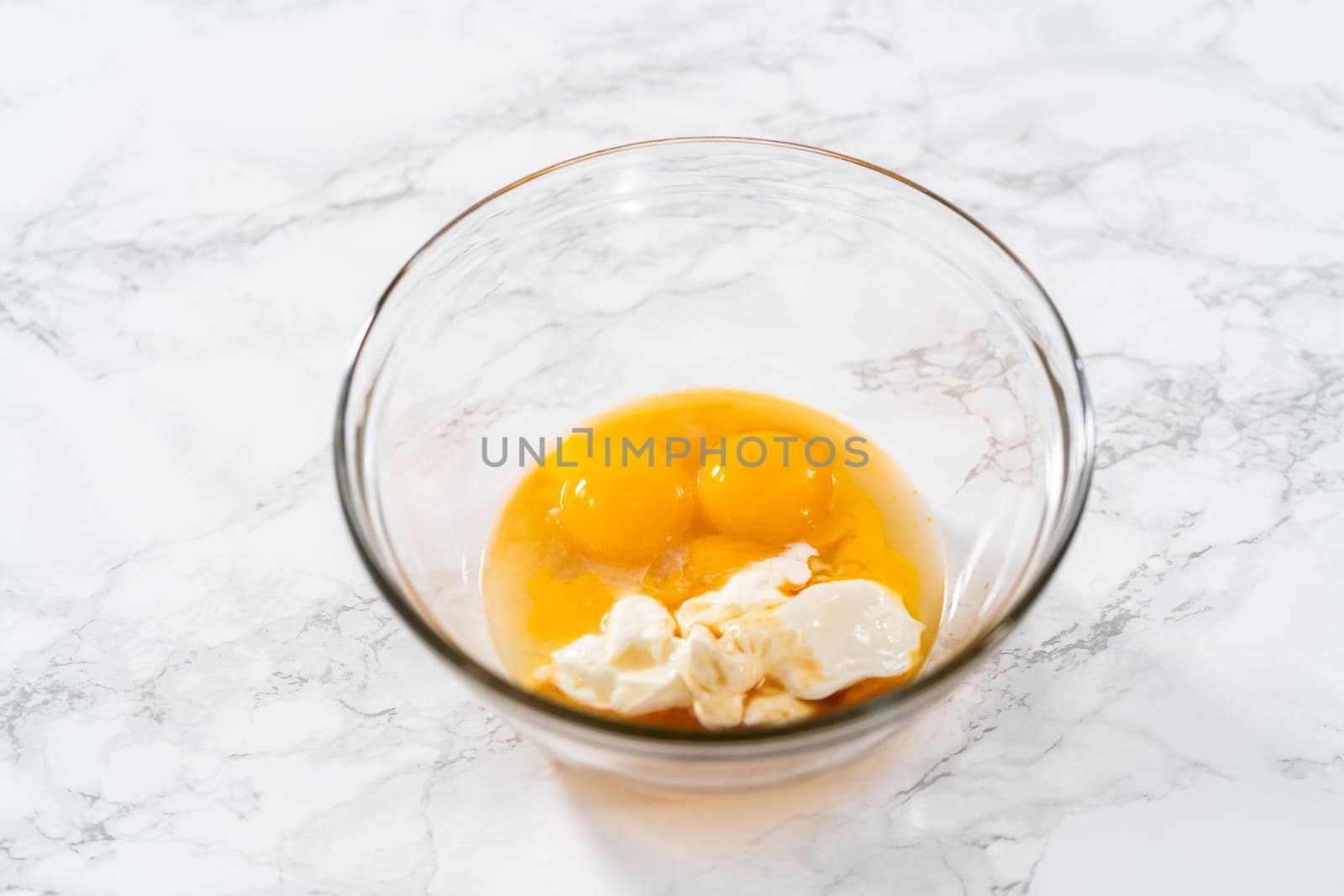 Lemon wedge cookies with lemon glaze. Mixing wet ingredients in a large glass mixing bowl to bake lemon wedge cookies.