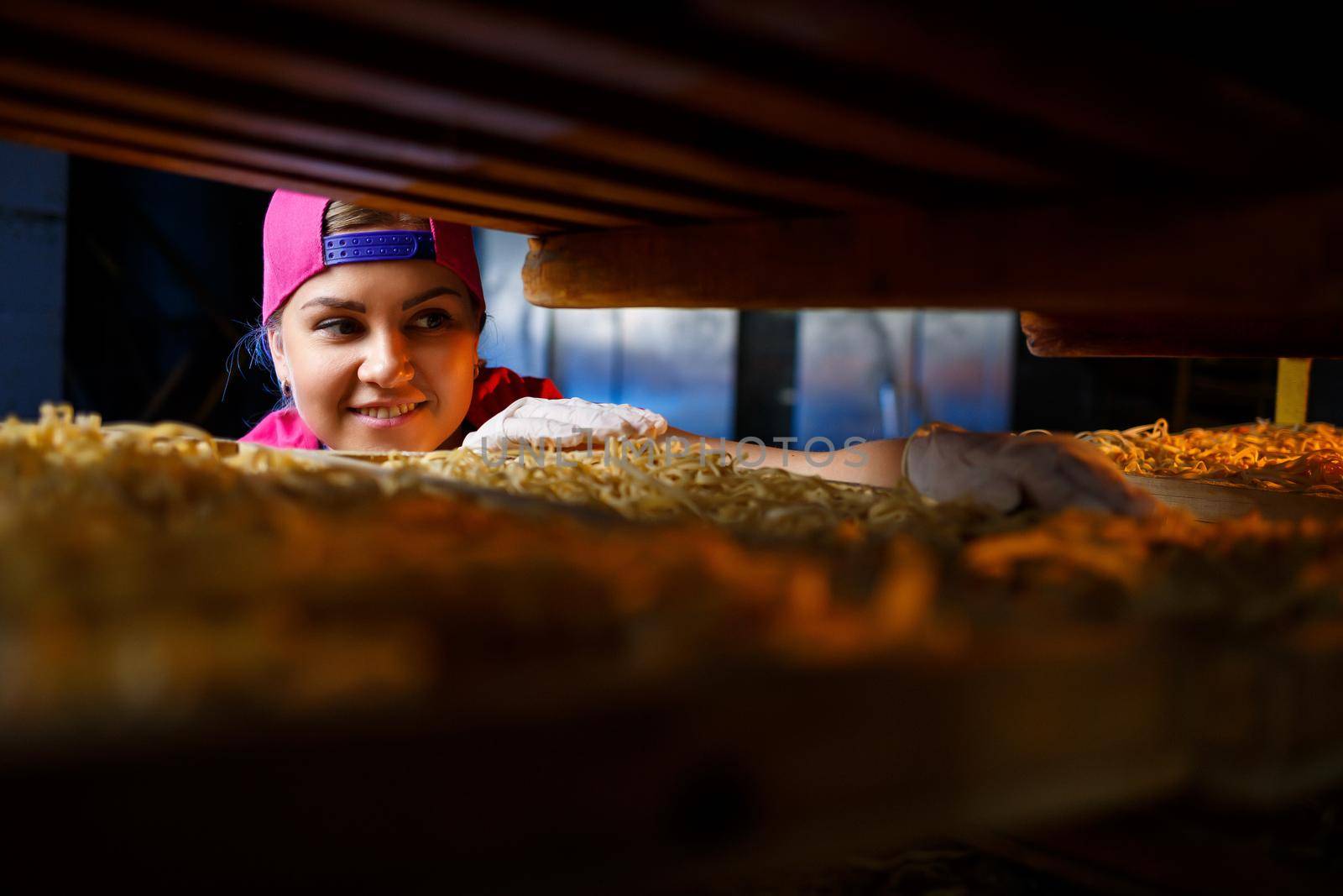 The girl works on the production of spaghetti. Making noodles. Pasta factory.