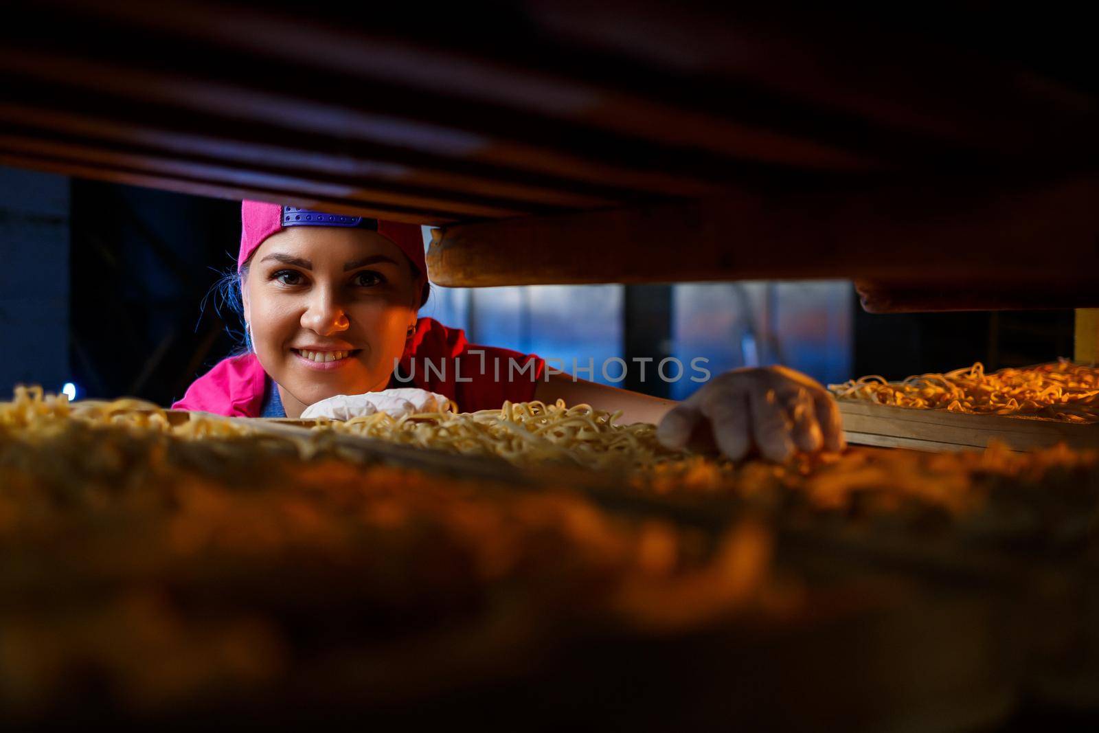 The girl works on the production of spaghetti. Making noodles. Pasta factory.