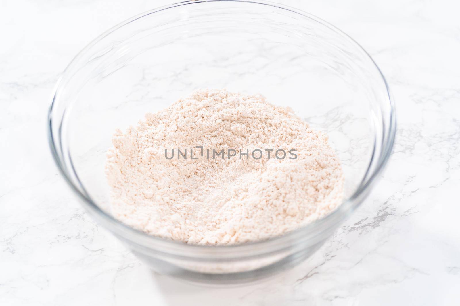 Mixing dry ingredients in a large glass mixing bowl to bake soft oatmeal raisin walnut cookies.