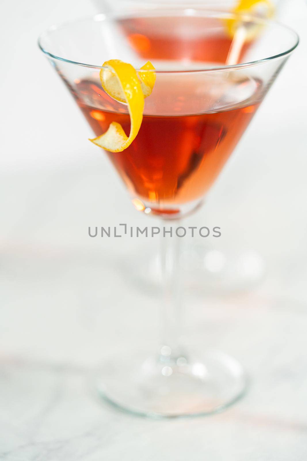 Cosmopolitan cocktail in a martini glass and decorated with a lemon swirl.