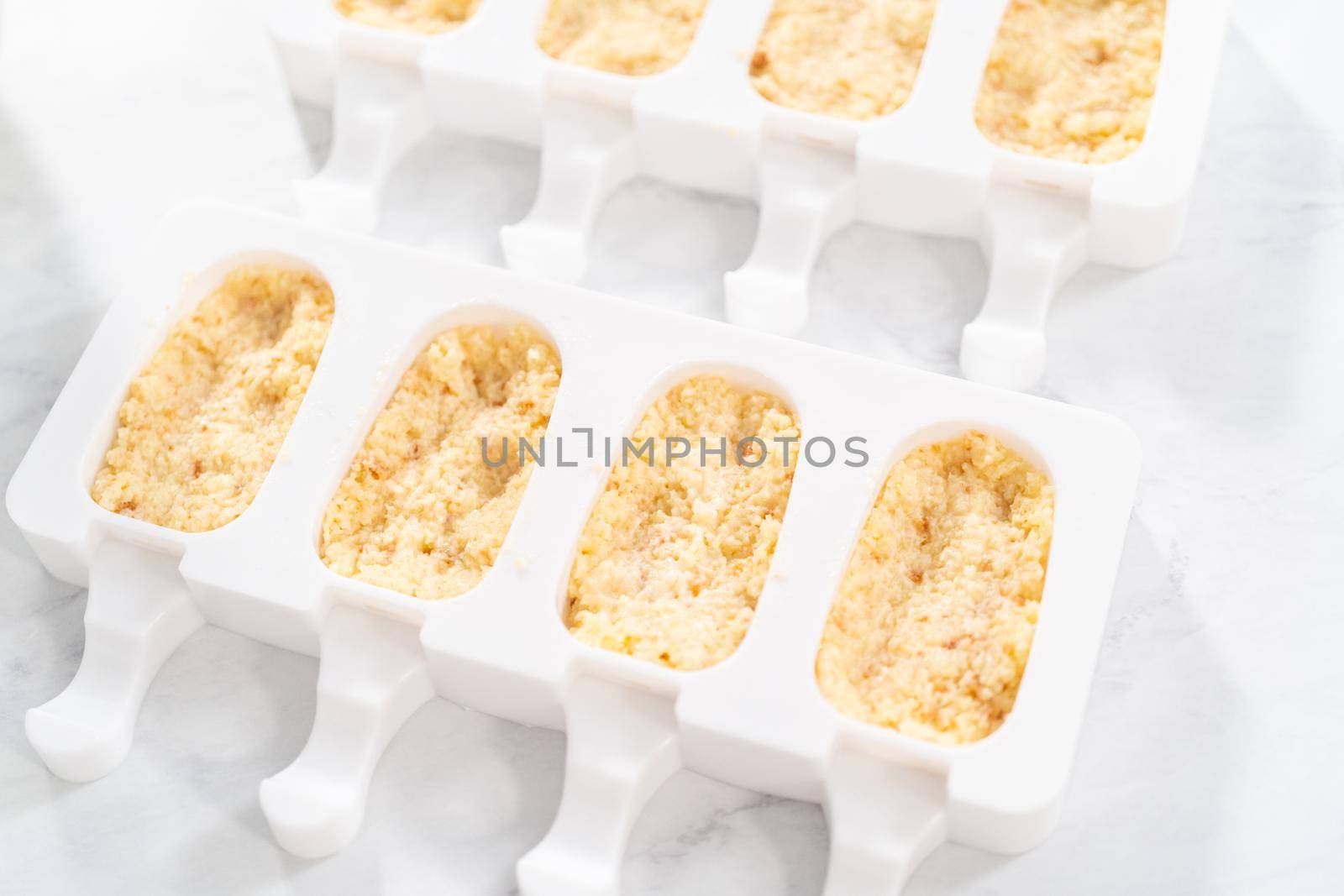 Filling silicone molds with cake crumbs to prepare mermaid cakesicles.