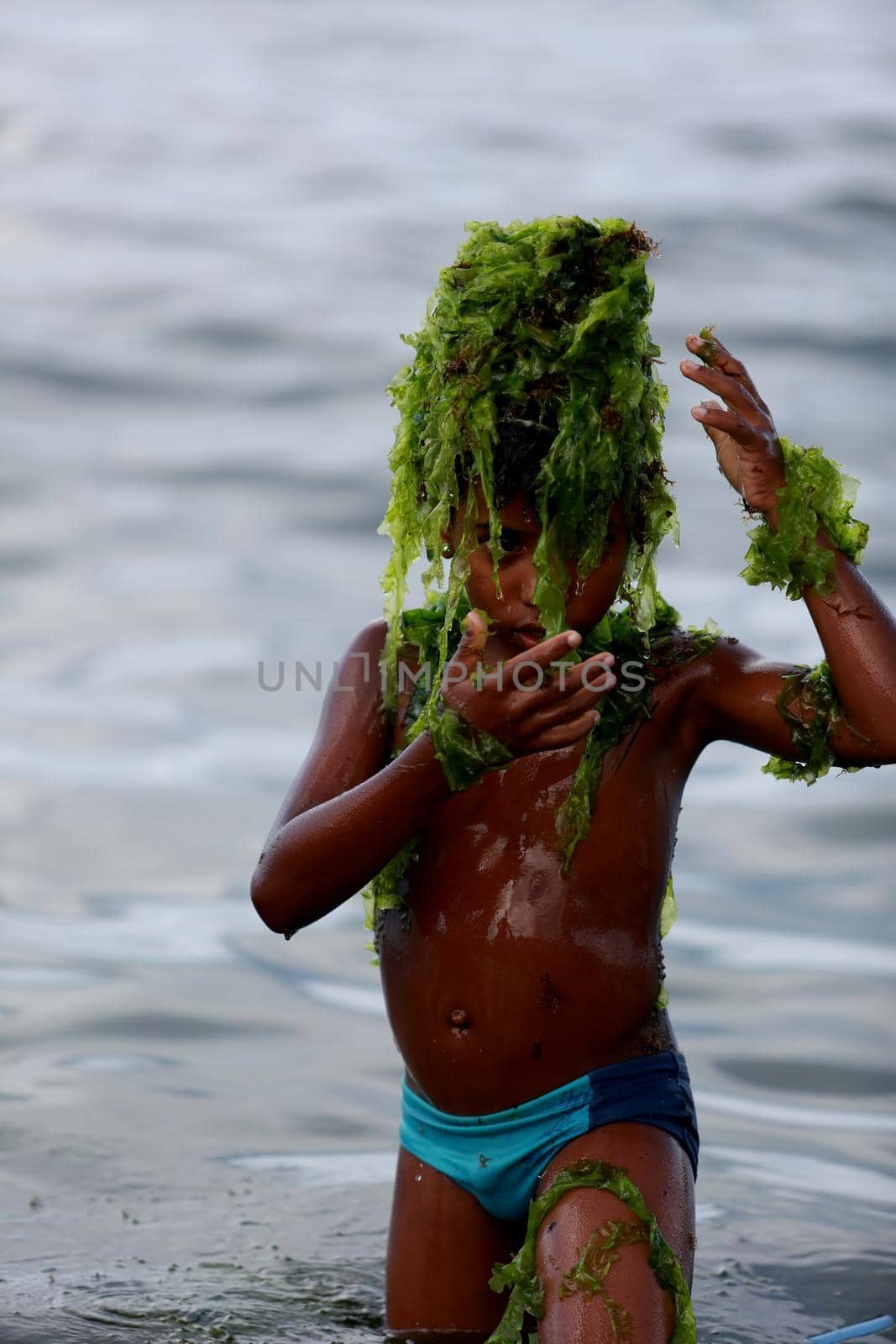 child playing with aquatic plant on the beach by joasouza