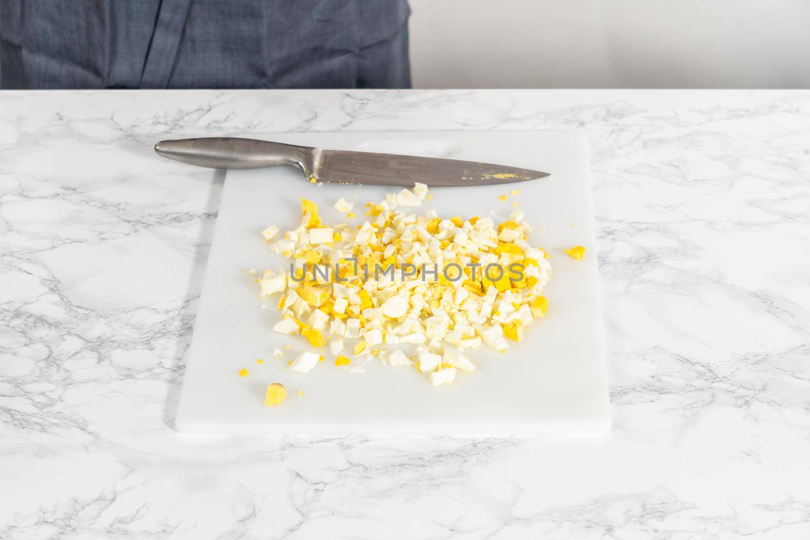 Cutting hard-boiled eggs in a shape of a loaf on a white cutting board.