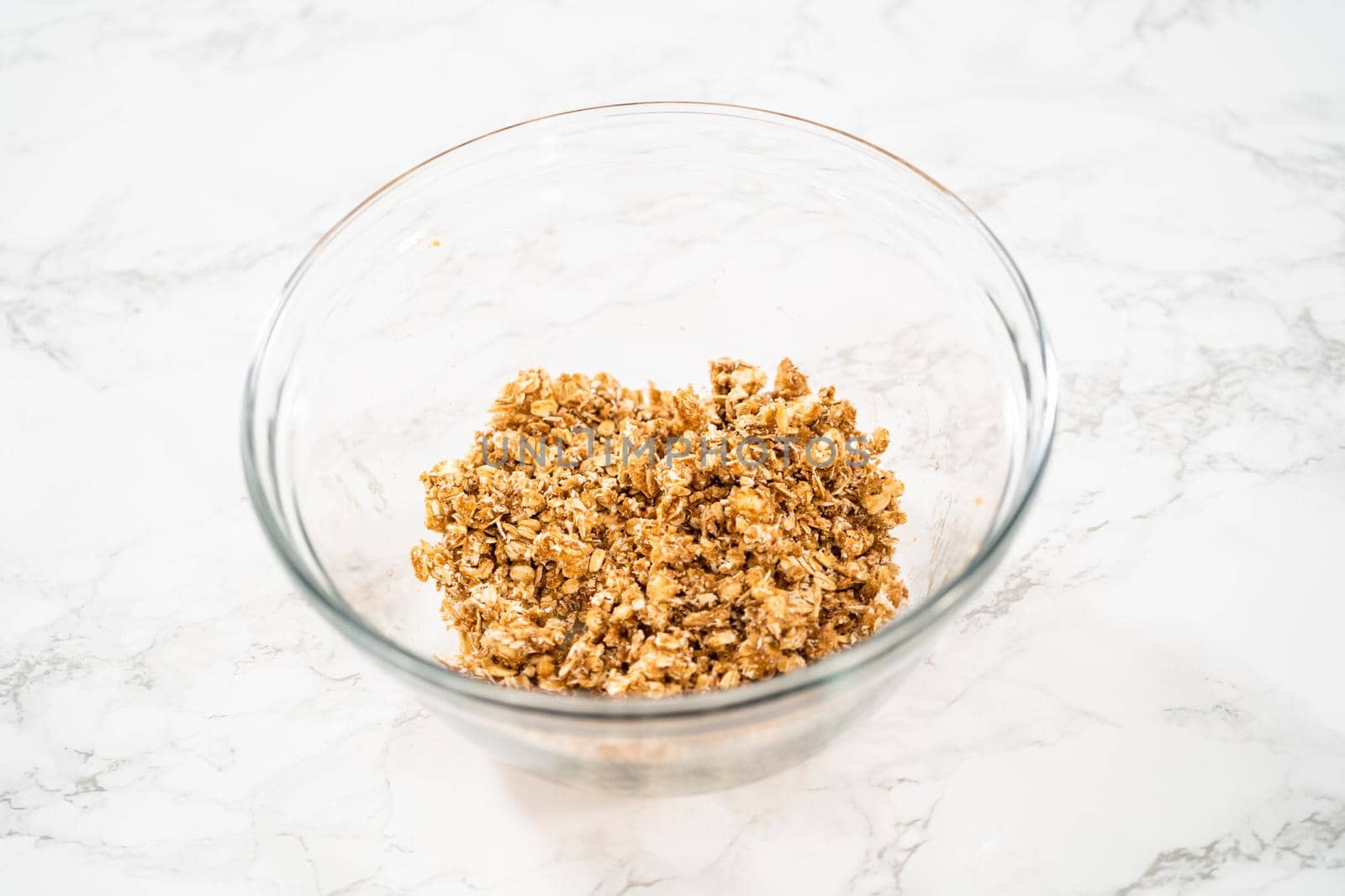 Mixing ingredients in a large glass mixing bowl to bake banana oatmeal muffins.