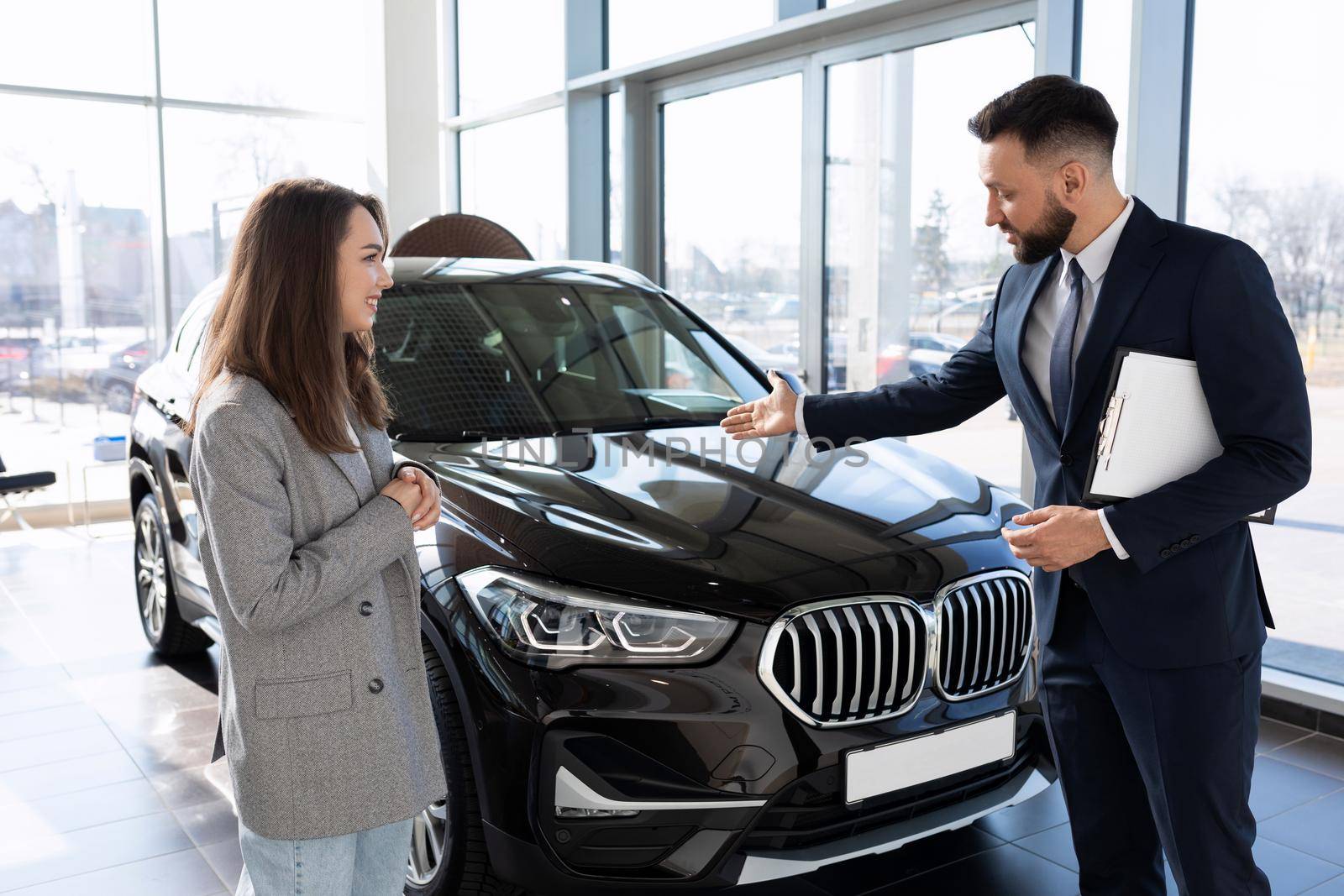 a salesman in a car dealership talks about the benefits of a new SUV to a buyer.