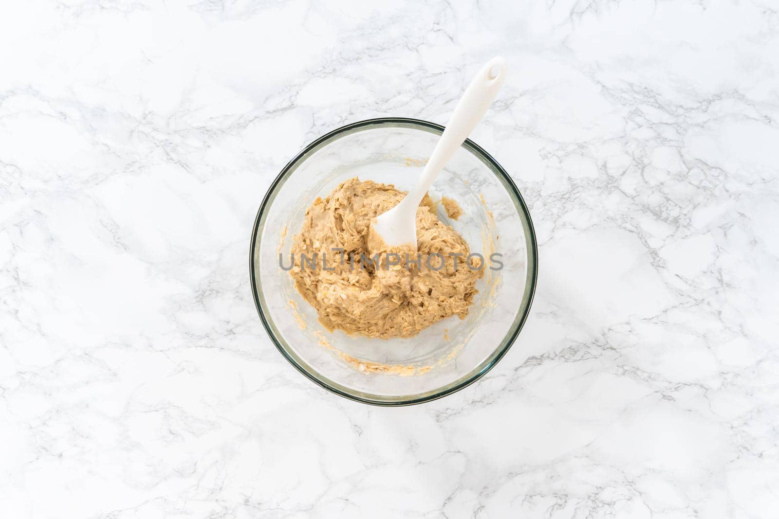 Flat lay. Mixing ingredients in a large glass mixing bowl to bake banana oatmeal muffins.