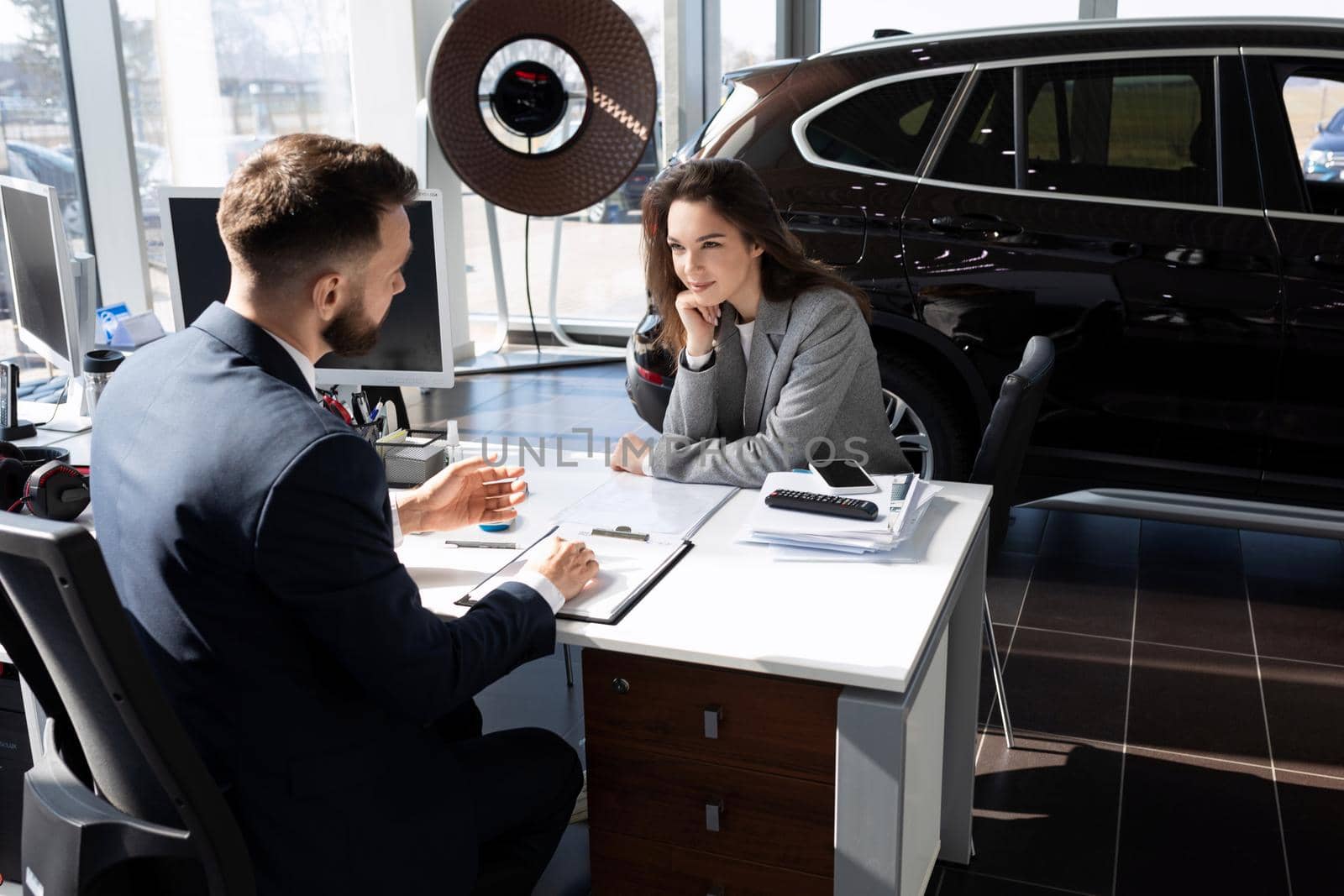 a young girl buys a car in a car dealership on credit and arranges it with a manager.