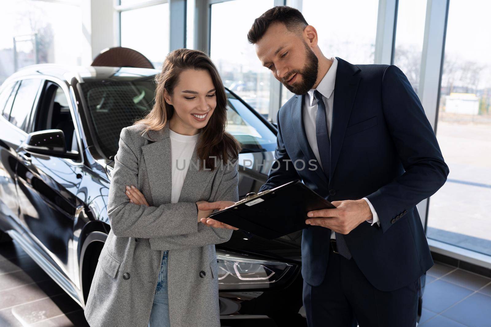 car dealership consultant talks about the loan program to the buyer of a new car.