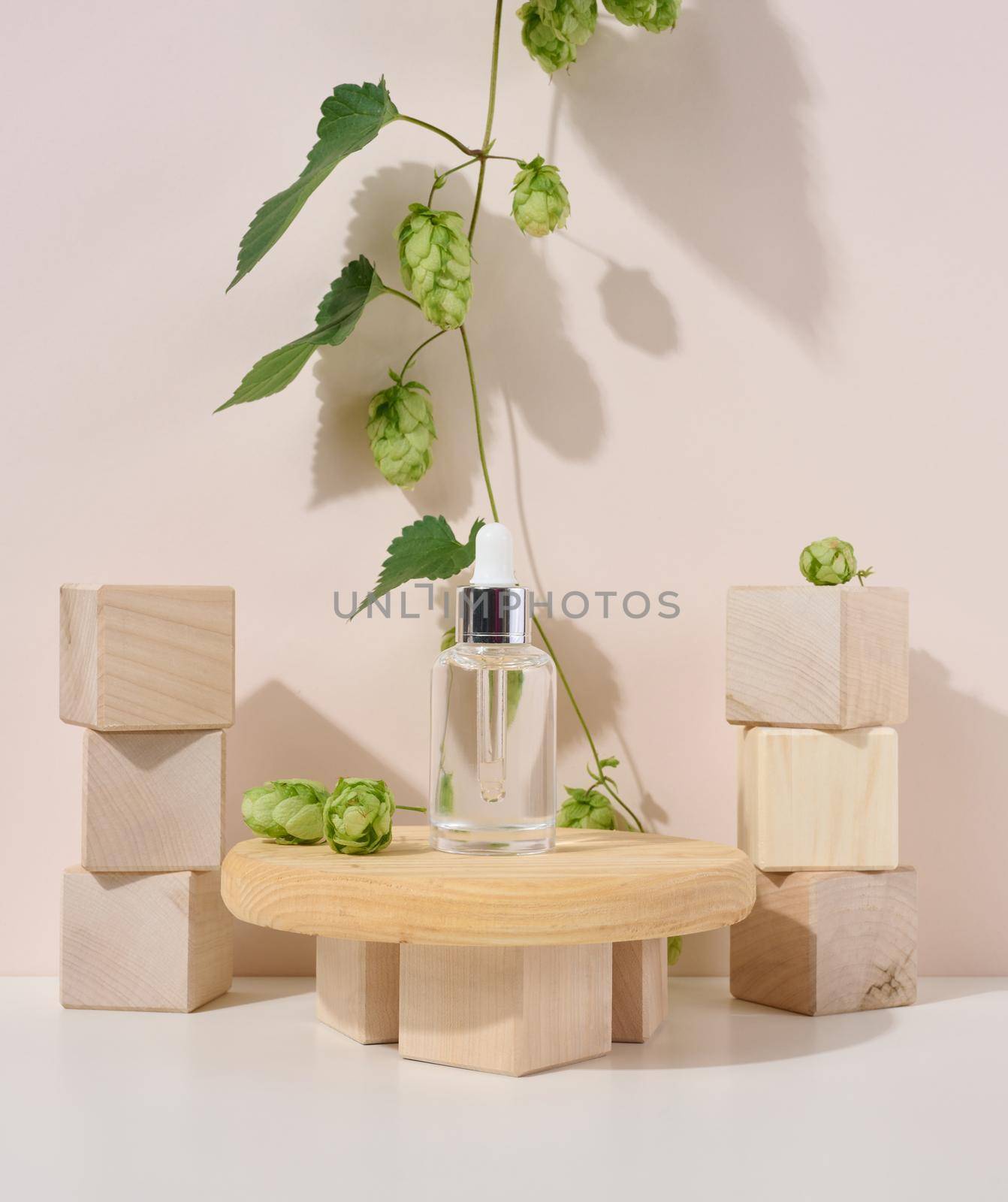 A white glass bottle with a pipette on a beige background. Containers for cosmetics, oils, serums