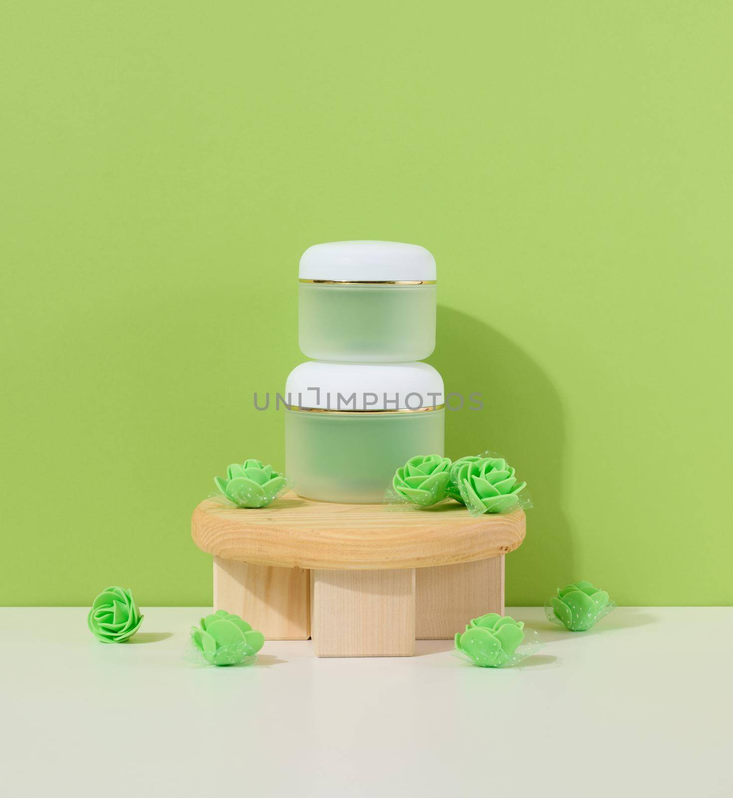 Green jar for cosmetics on a white table. Packaging for cream, gel, serum, advertising and product promotion