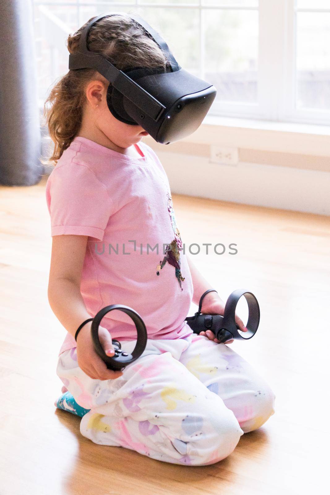 Little girl playing virtual reality game in the living room,
