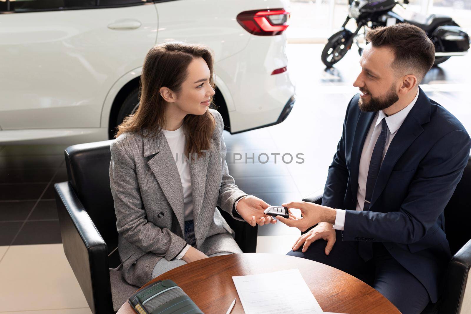 car dealership manager handing over keys to new car buyer.