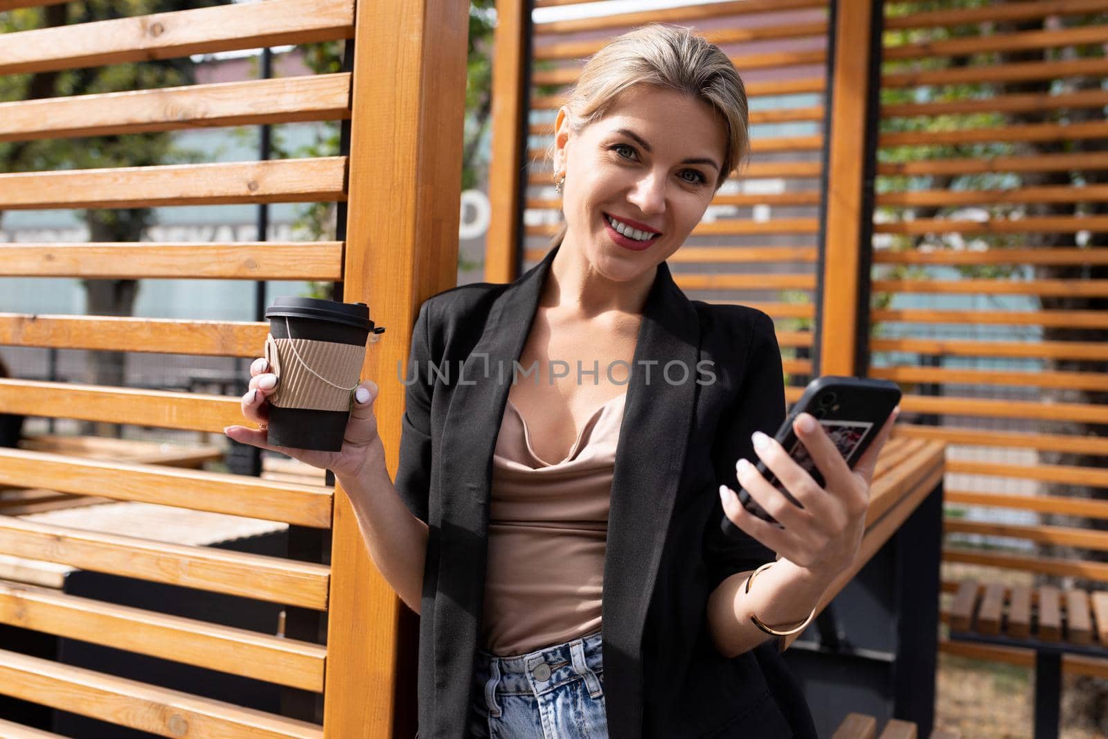 close-up portrait of a successful middle-aged business woman in a city cafe with a phone and a glass of coffee.