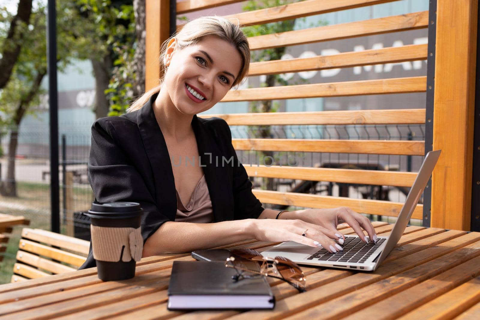 portrait of a charming woman working on a laptop in a cafe with a glass of coffee.