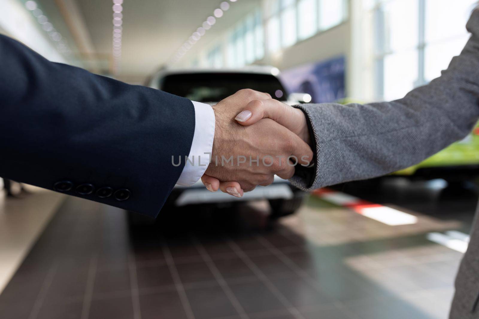 handshake against the backdrop of a car dealership at a deal, the concept of buying a car on lease by TRMK