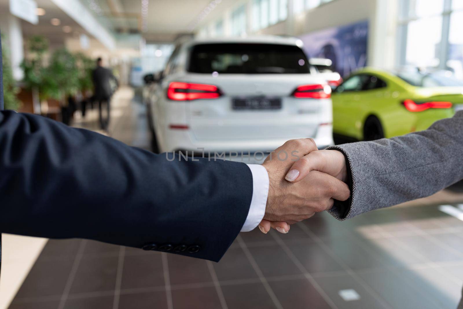 buyer and seller at car dealership shaking hands after buying a car by TRMK