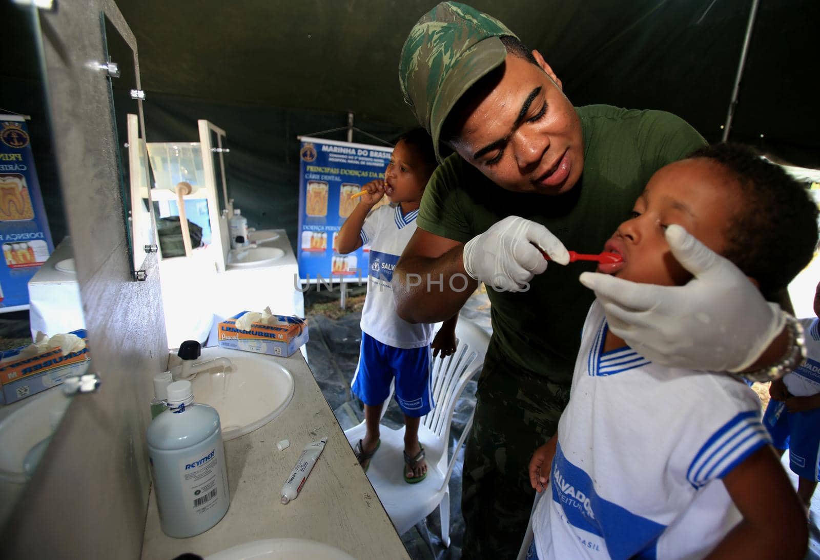 salvador, bahia / brazil - november 4, 2015: military man from the brazilian navy teaches a child to brush his teeth during social action on the island of Mare in the city of Salvador.
