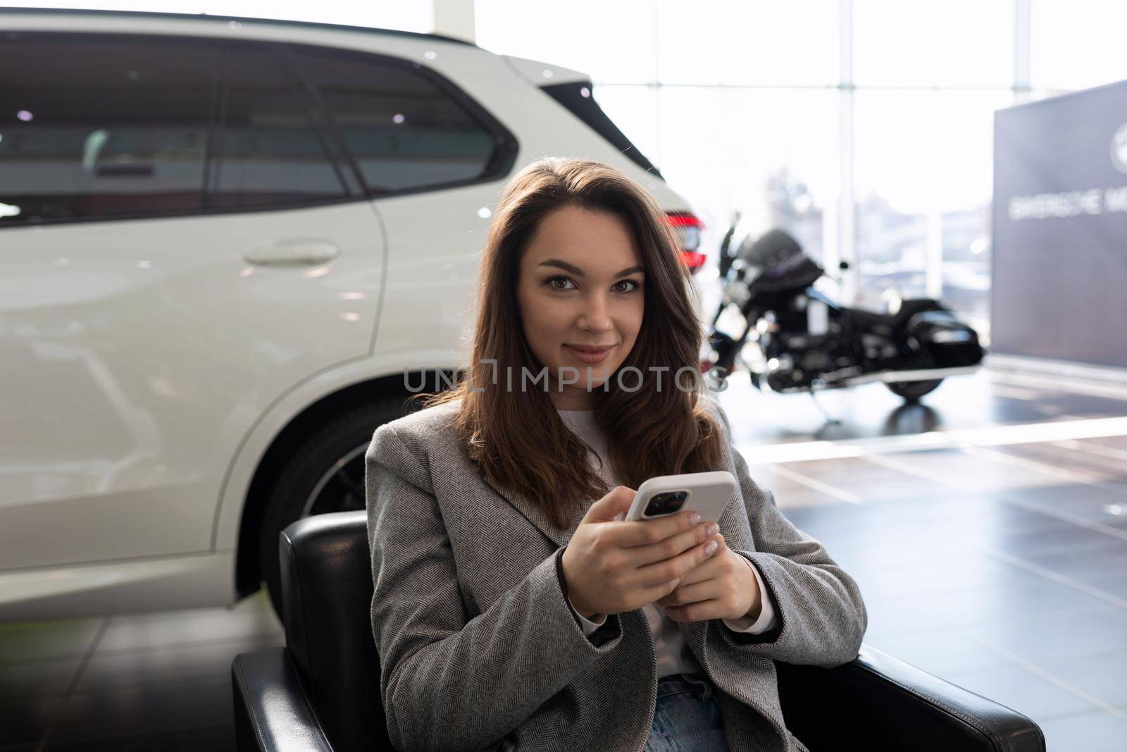 young woman in a car dealership waiting for a sales manager of new cars.