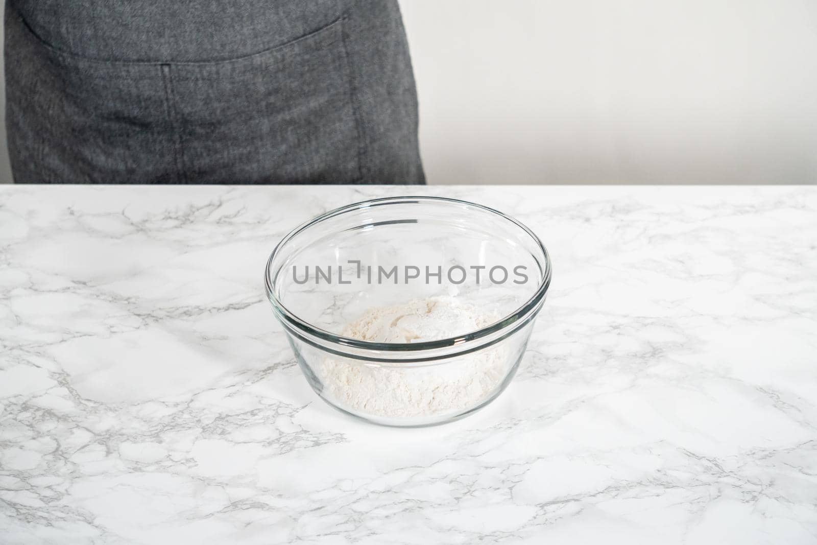 Mixing ingredients in a large glass mixing bowl to bake banana oatmeal muffins.