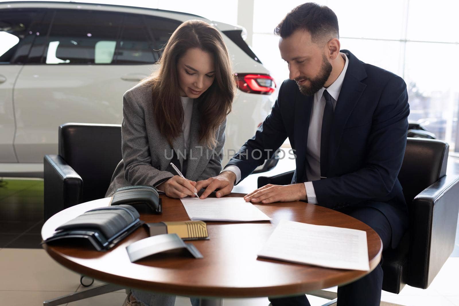young woman and car sales manager sign a contract.