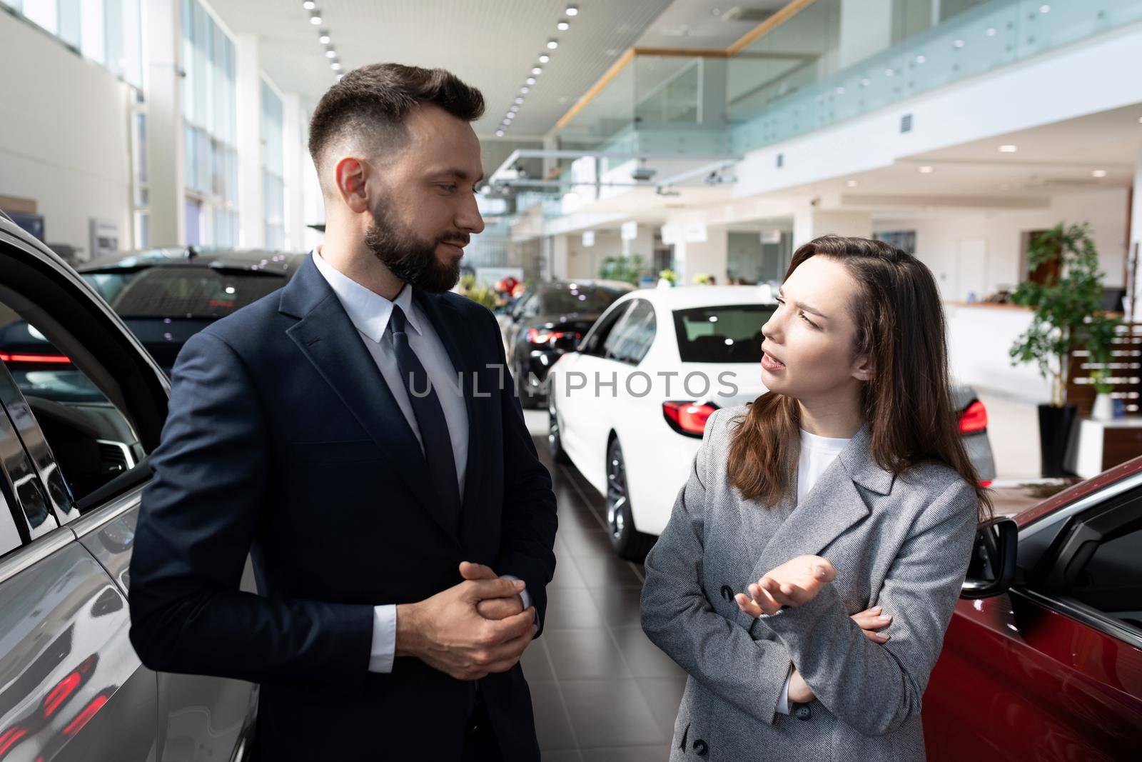 a young woman in a car dealership is interested in the terms of a loan to buy a new car.