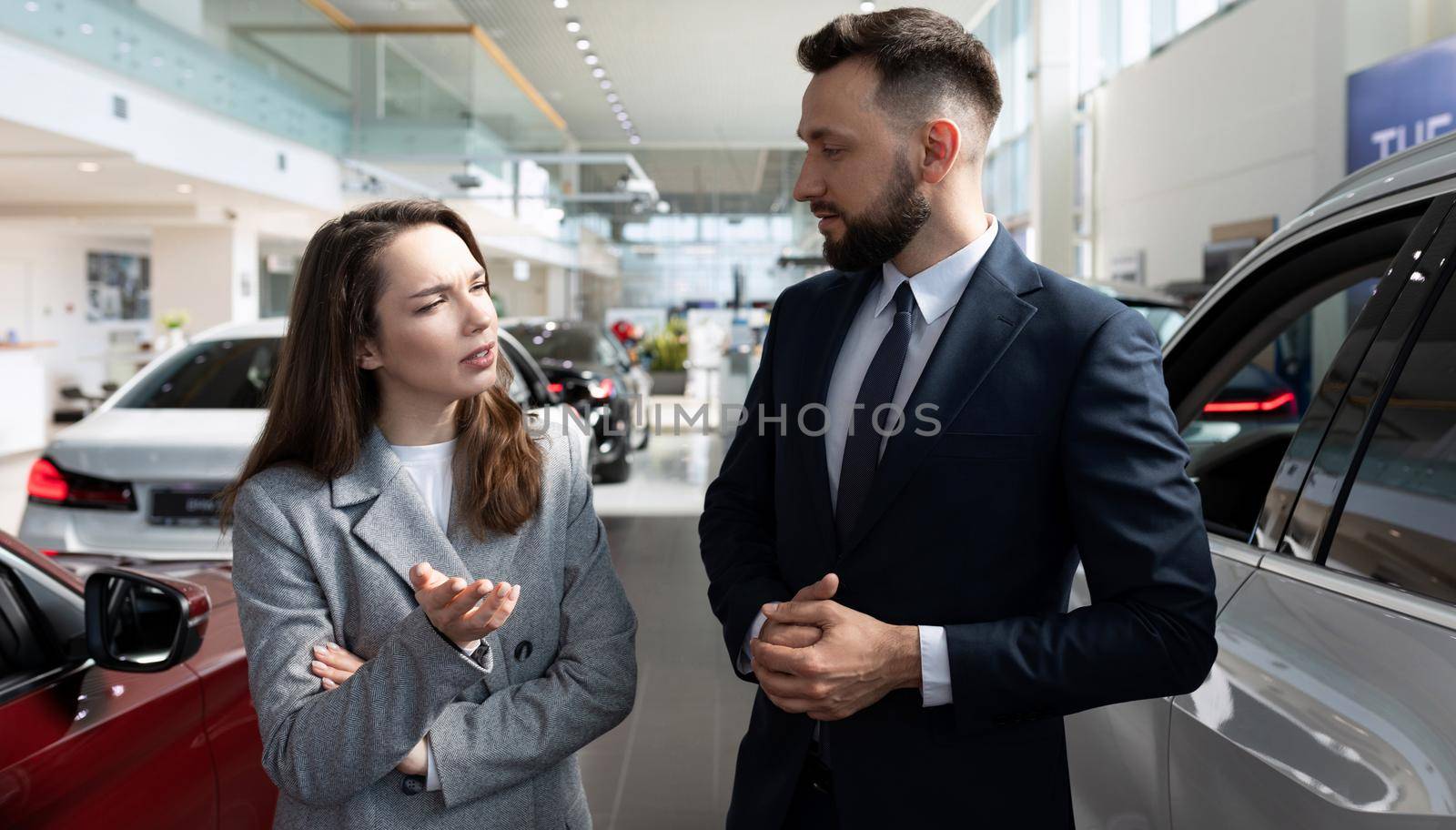 young woman in a car rental chooses a car for a long lease.