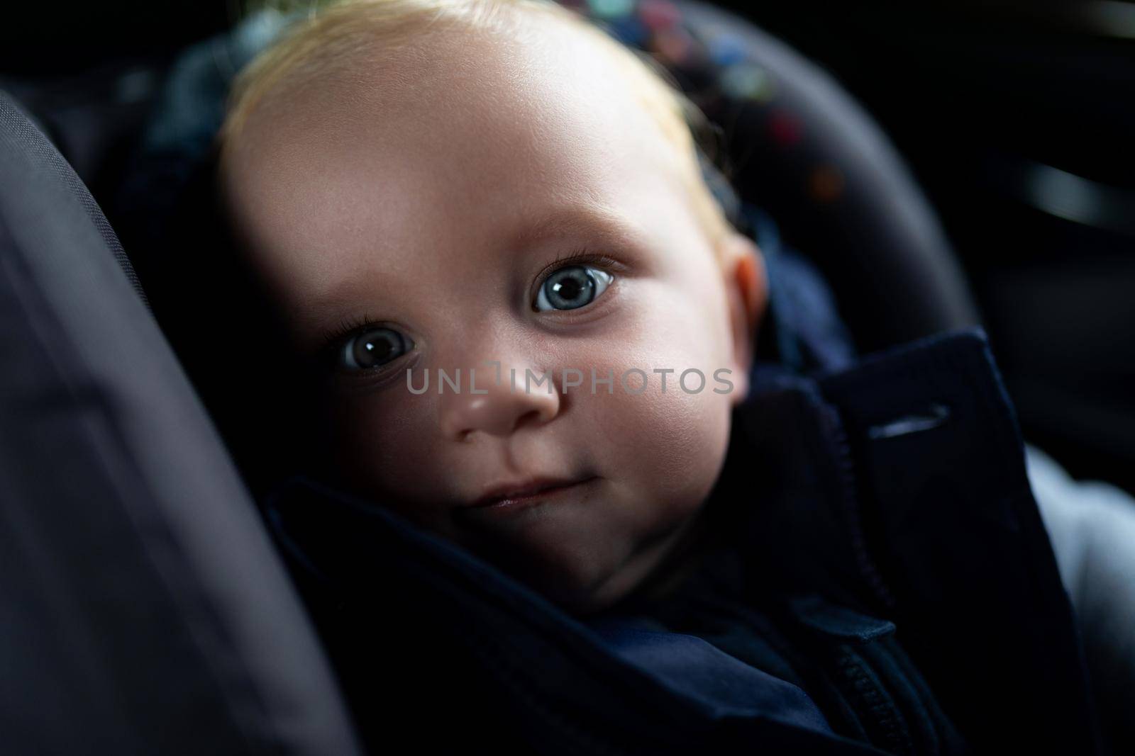 close-up portrait of a baby inside a car carrier.