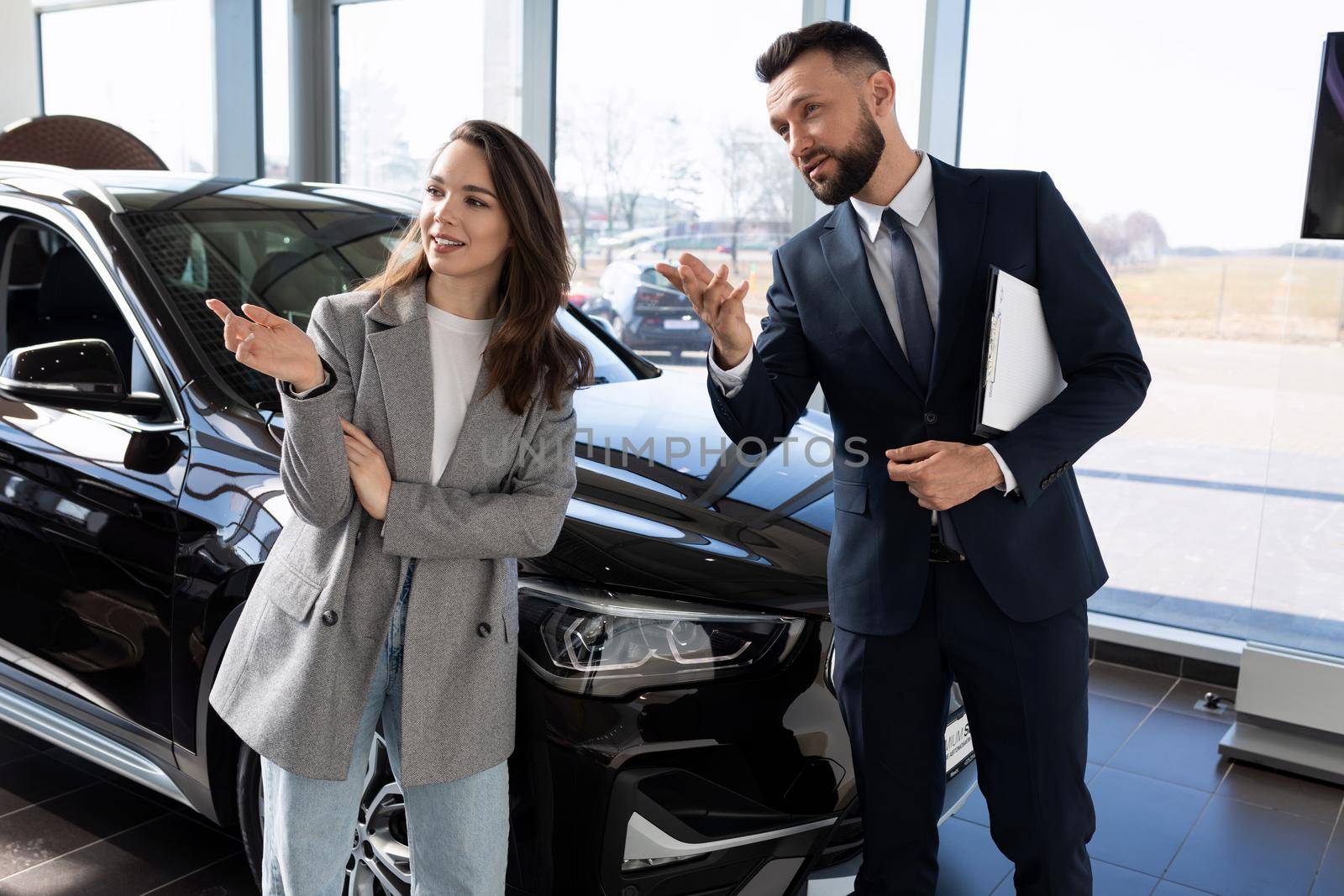 a young woman in a car dealership, together with an employee, a car dealer chooses a new car.