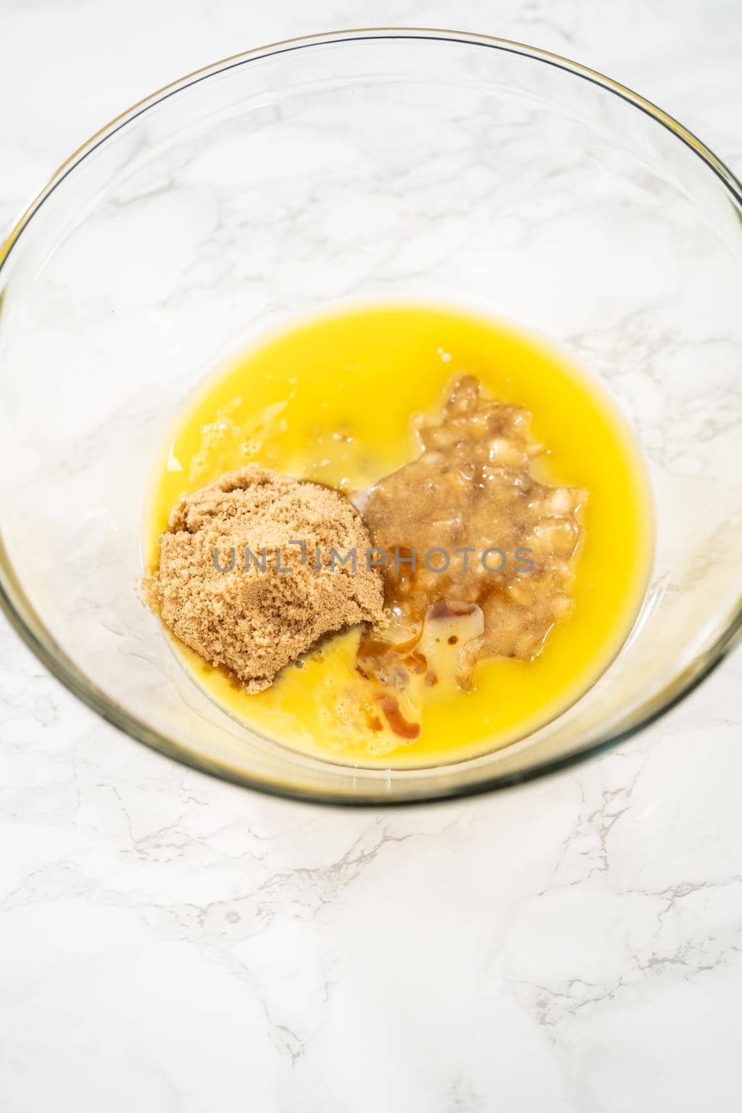 Mixing ingredients in a large glass mixing bowl to bake banana oatmeal muffins.