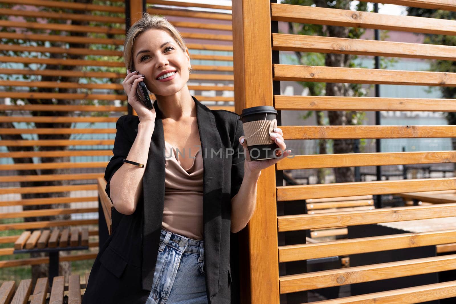 successful middle-aged woman during a lunch break in a cafe talking on the phone drinking coffee.